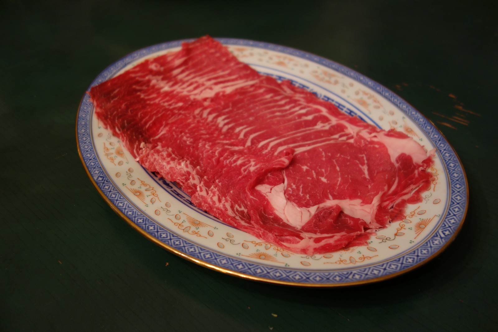 Present the meat in an appetizing fashion, ready to cook. If we slice it ourselves, we often lay it out in a more circular pattern. This is store-bought shabu shabu beef, pre-sliced.