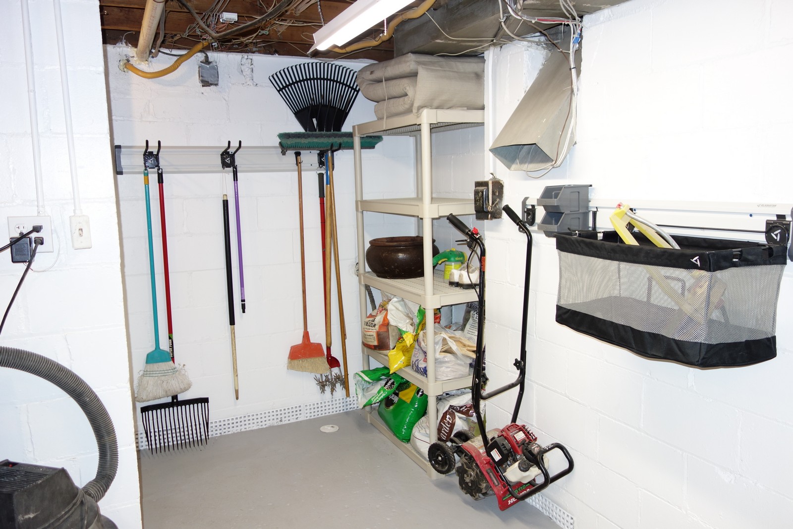 My "Gardening Corner". An S-Hook holds my heavy rototiller off the ground in my power tool room. That's nice because I am frequently sweeping up sawdust in here. Tool Hooks easily hold my brooms and yard tools, with lots of room to spare. I haven't decided yet how to use the 24-inch mesh basket that came in the Accessory Kit - will probably put sprinklers and various hose nozzles in it.