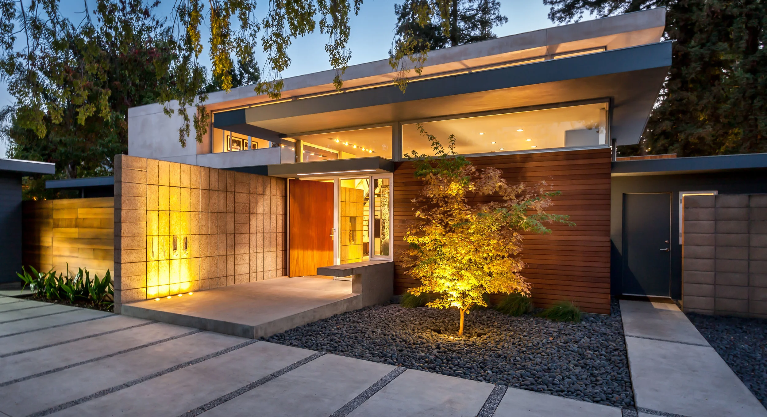 The warm cedar, polished concrete block and wide mahogany pivot door invite you in.
