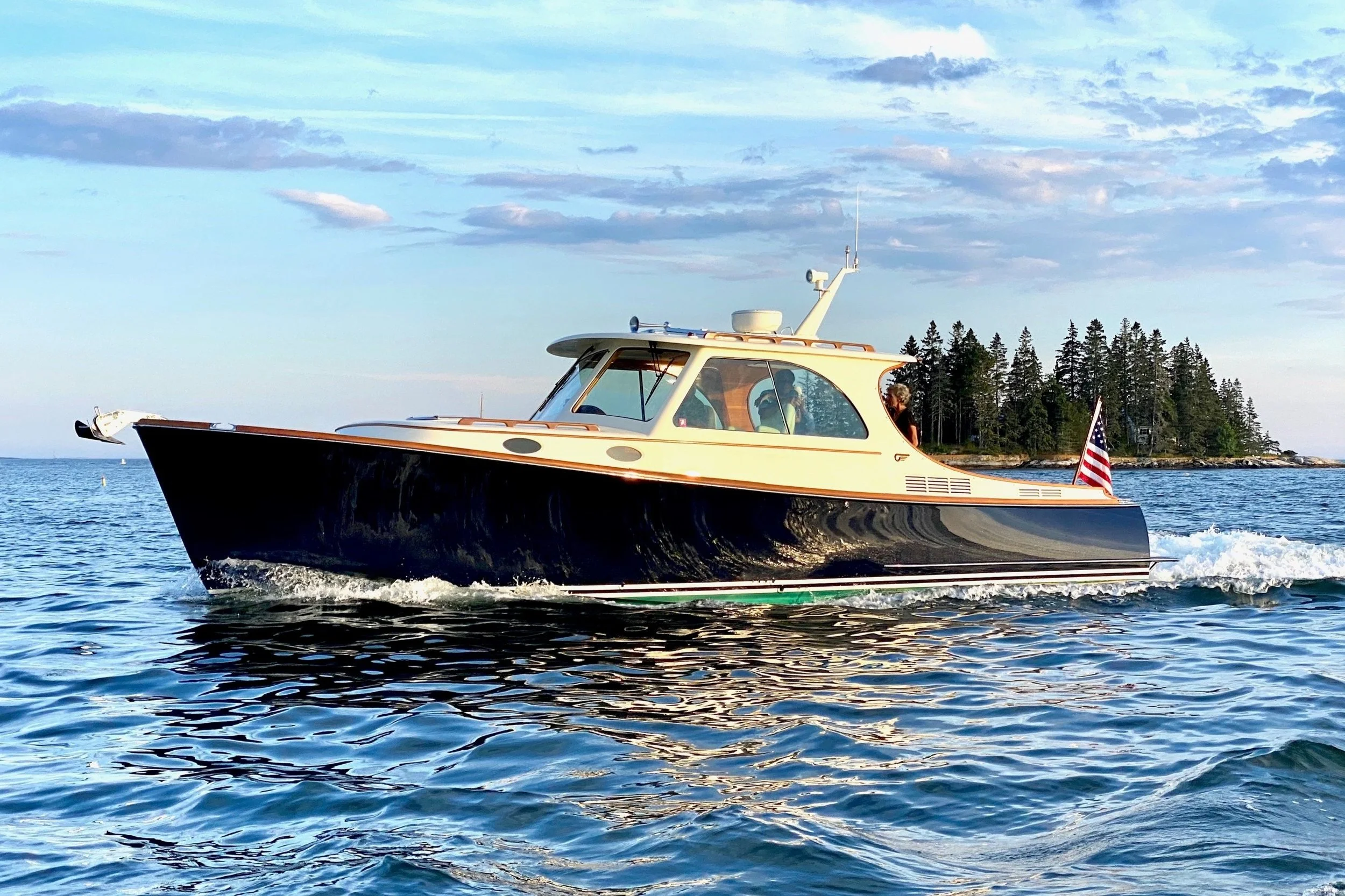 A luxury motorboat cruising on the ocean with an American flag at the stern, under a clear blue sky.