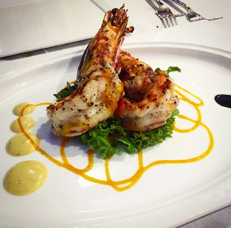Jumbo shrimps roasted in a clay oven over a bed of local greens and served with a roasted garlic aioli and a Cayman honey lemon drizzle.