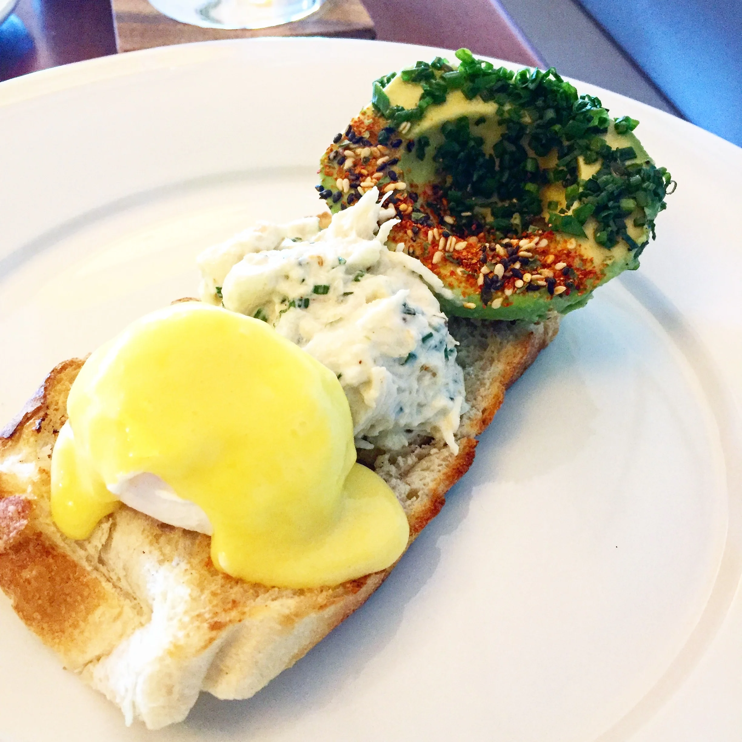 Poached egg with hollandaise, light crab salad and togarashi sprinkled avocado all on a crusty bread.