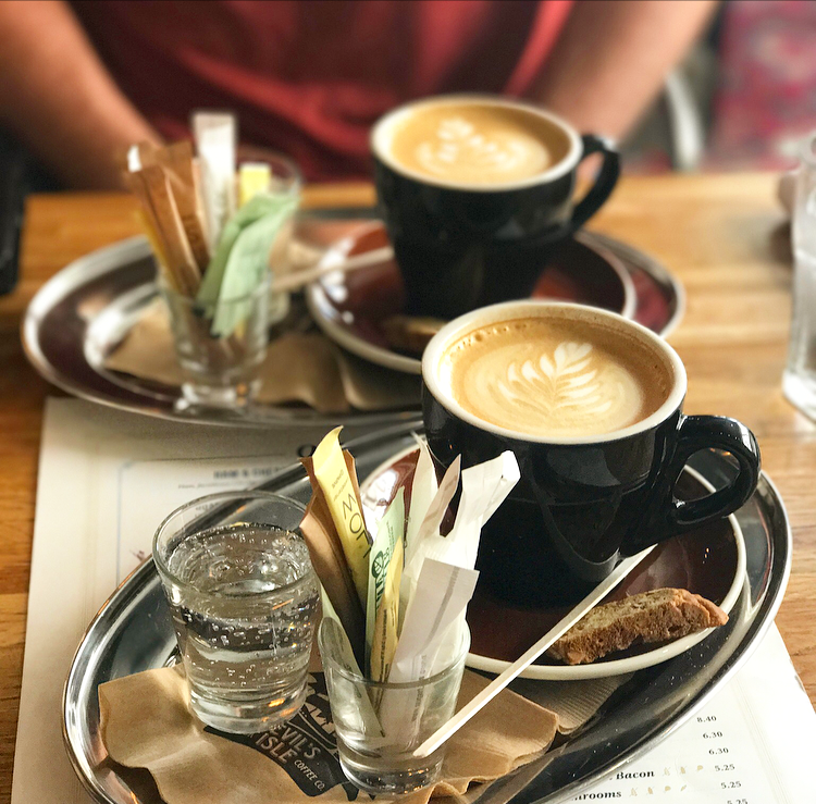 Lattes served with biscotti and sparkling water