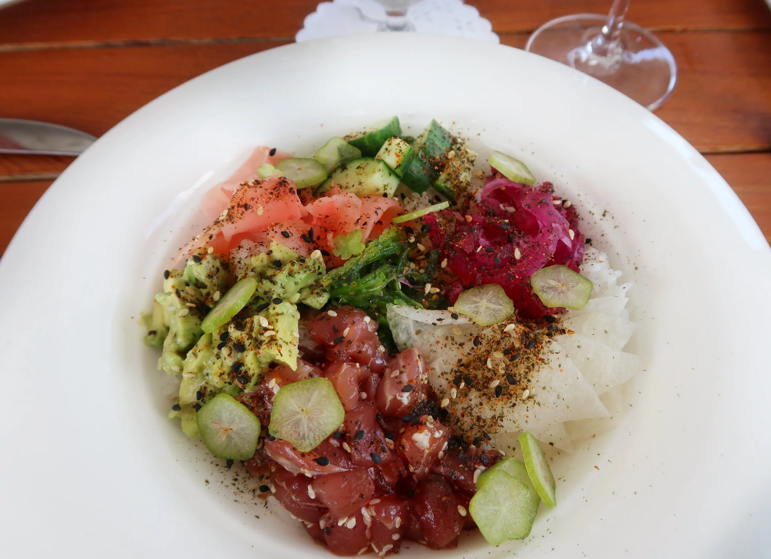 A refreshing and light Tuna Poke Bowl - Yellowfin tuna, rice, wakame seaweed salad, avocado, pickled vegetables, furikake and herbs.