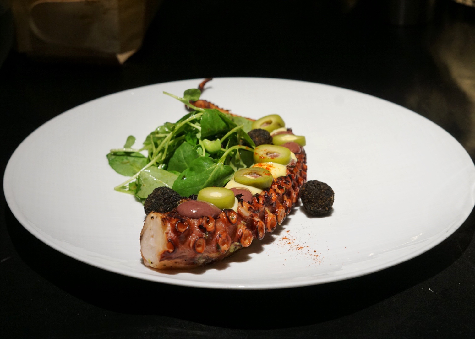 The tender Grilled Octopus is served with chimichurri, olive sauce, aji amarillo aioli and squid ink potato croquettes.