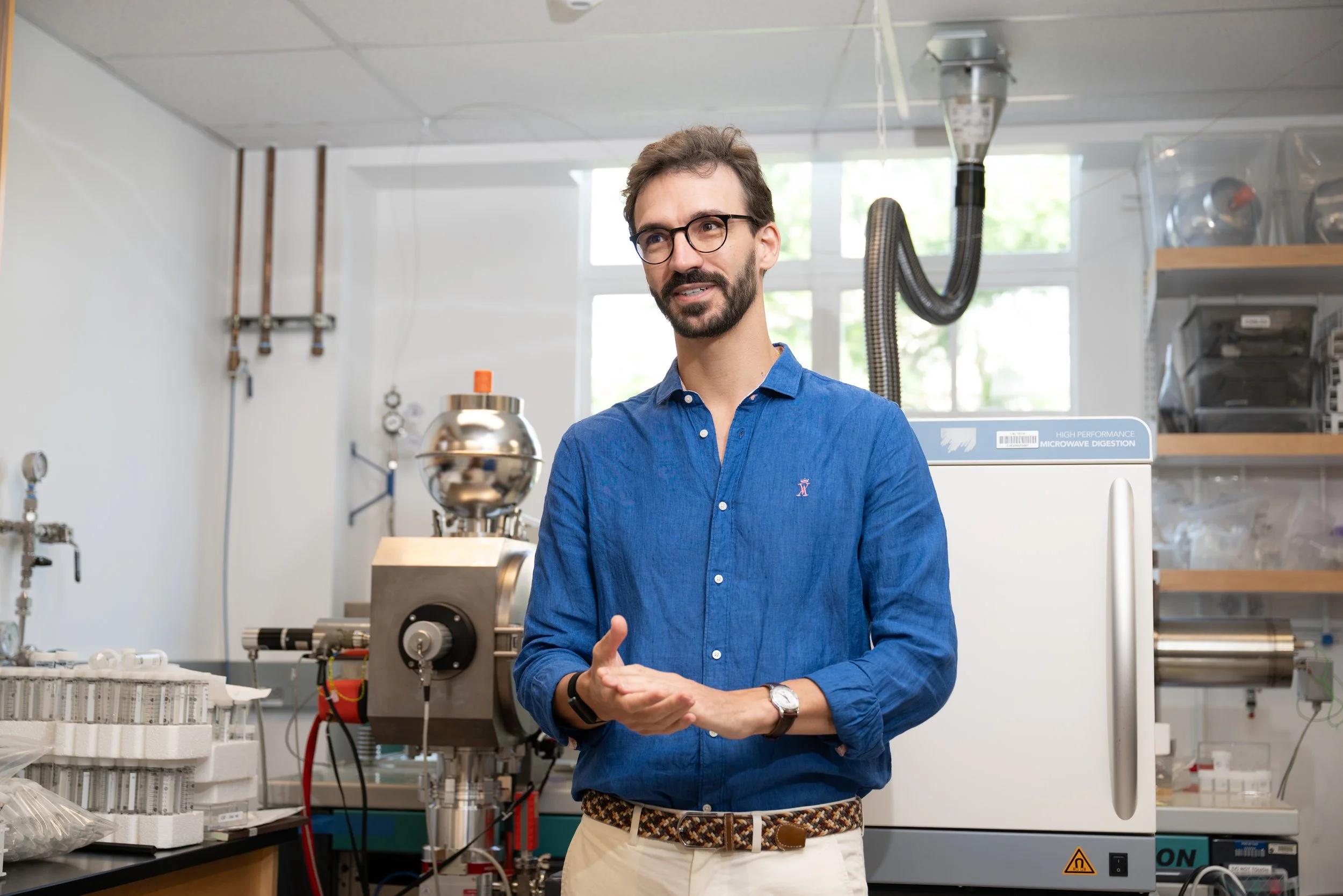 Color photograph of Caltech geochemist François Tissot standing in his laboratory in front of scientific instruments.