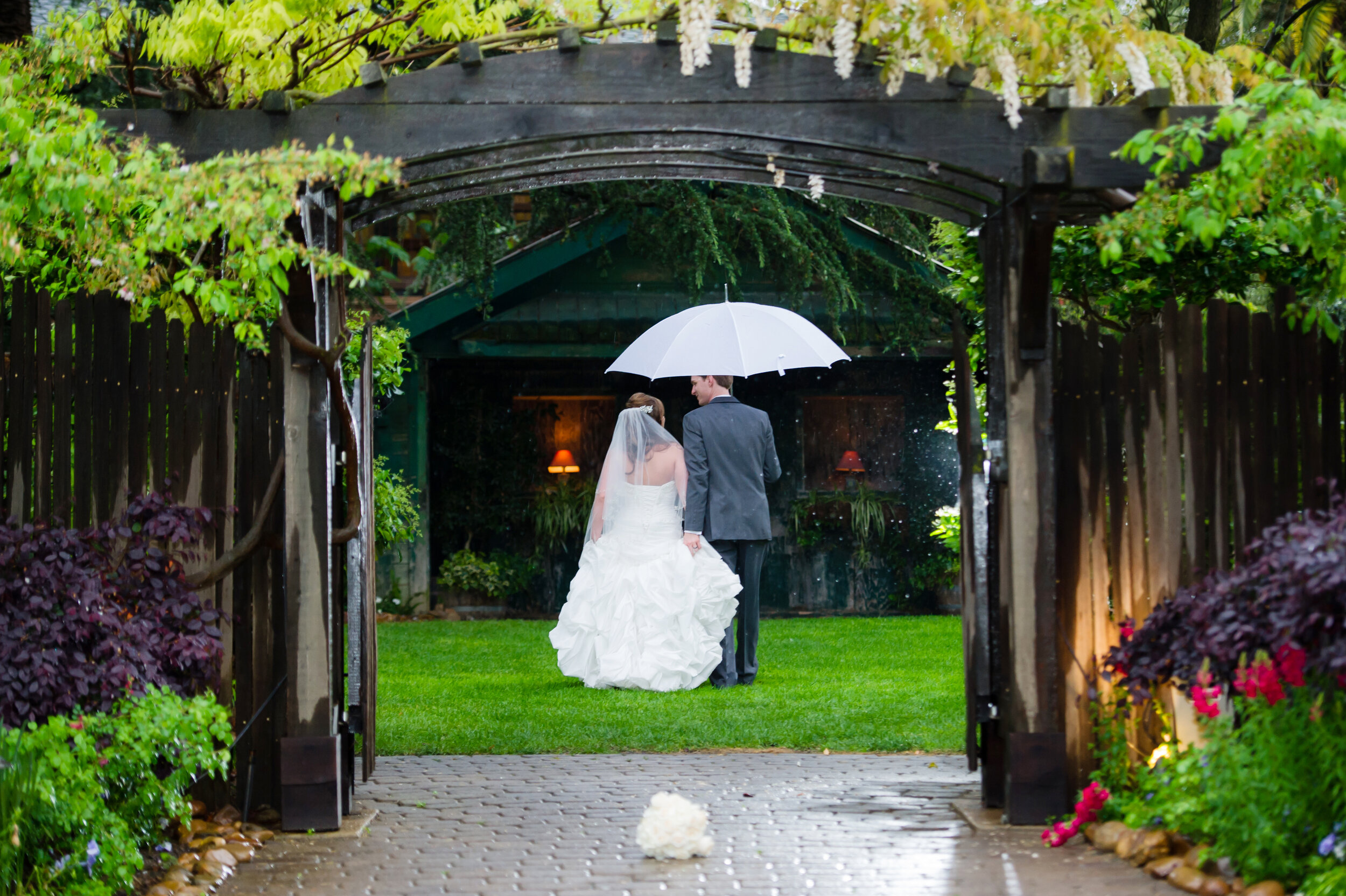 Photo of a bride and groom outdoors with an umbrella