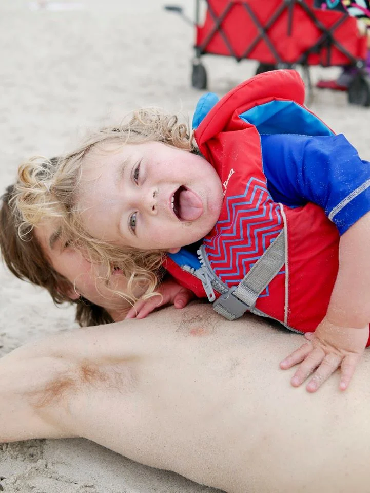 Sky LOVES the beach.. mostly runs in and out of the waves and laughs, but he also finds time to eat sand and climb on papa, photo by Sarina Partridge