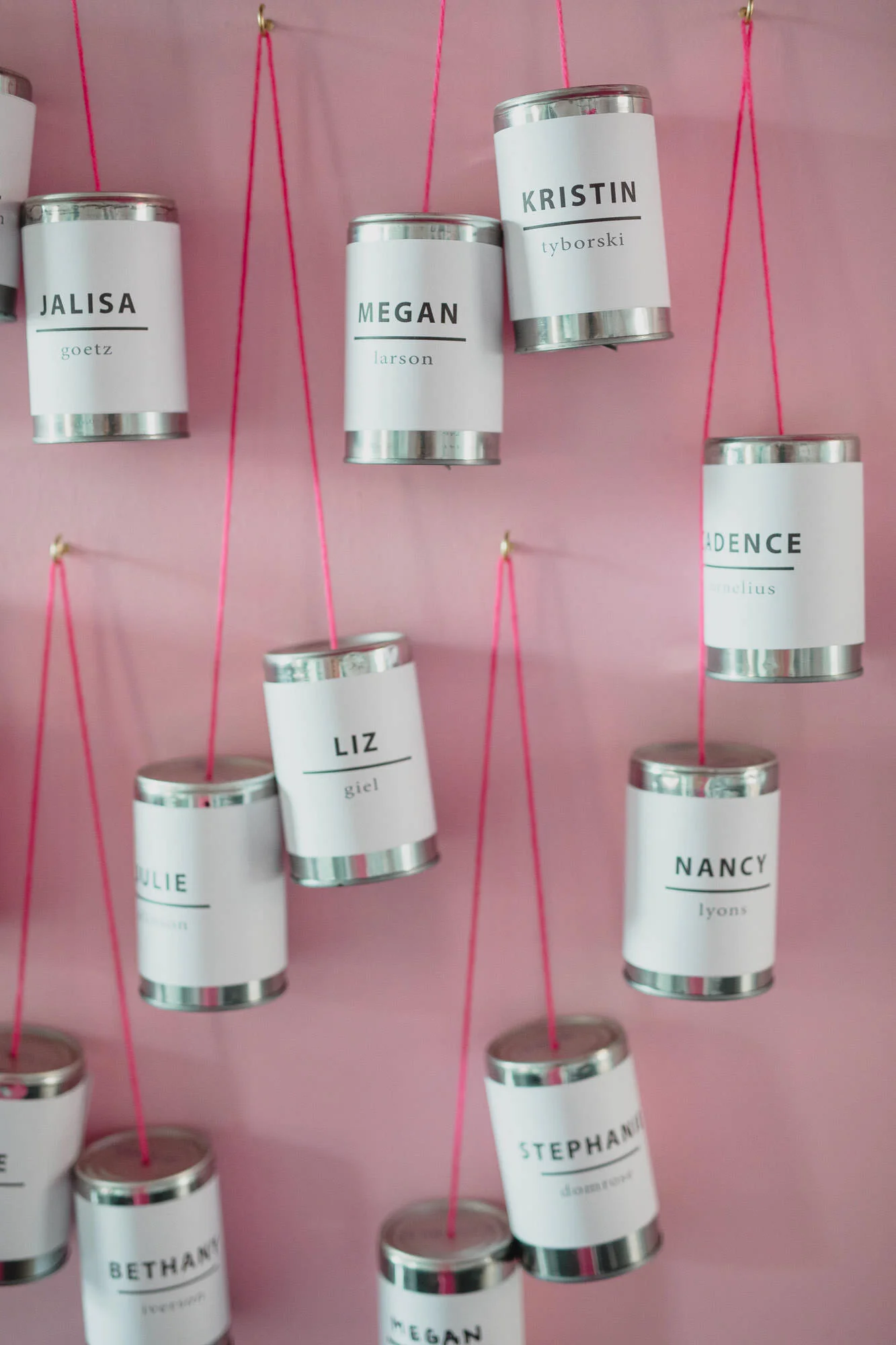  tin can telephones hang from pink string on pink wall 