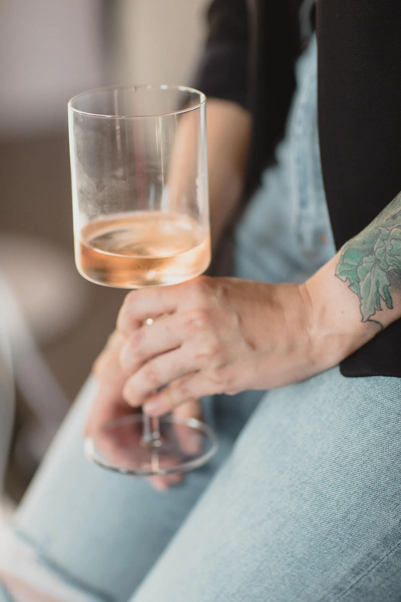  tattooed womxn holds glass of rose in square bottom wine glass 