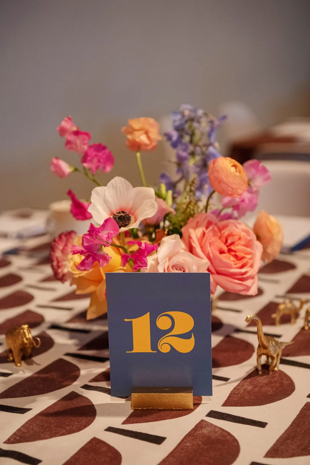  tabletop display with brown and white graphic print table cloth, dinosaur figurines, and spring floral centerpiece. 