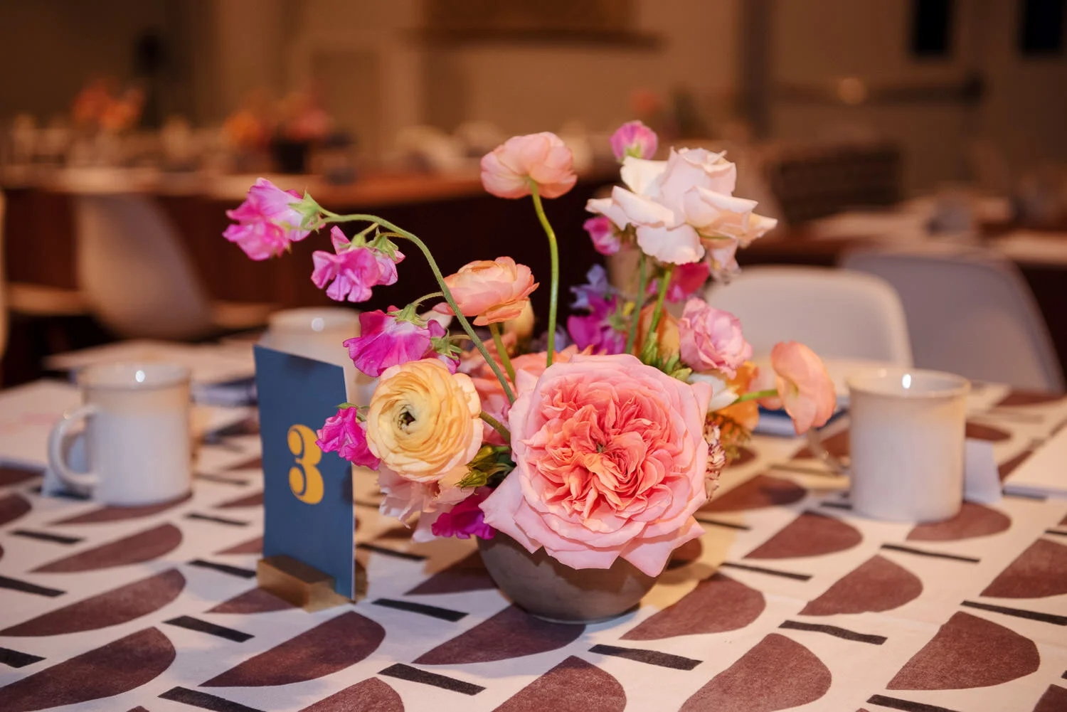  tabletop display with brown and white graphic print table cloth, dinosaur figurines, and spring floral centerpiece. 
