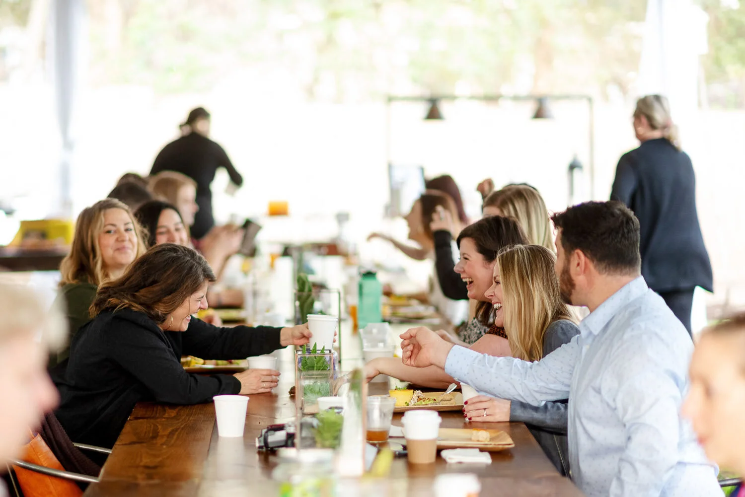  conference attendees laugh over wooden table 