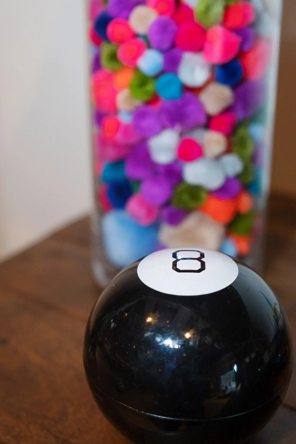  magic 8 ball in front of vase full of colorful poms 