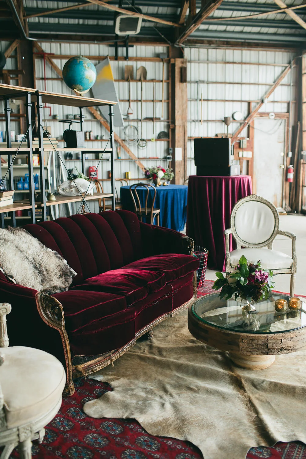  lounge setup with vintage velvet red couch, glass topped coffee table, bear skin rug  