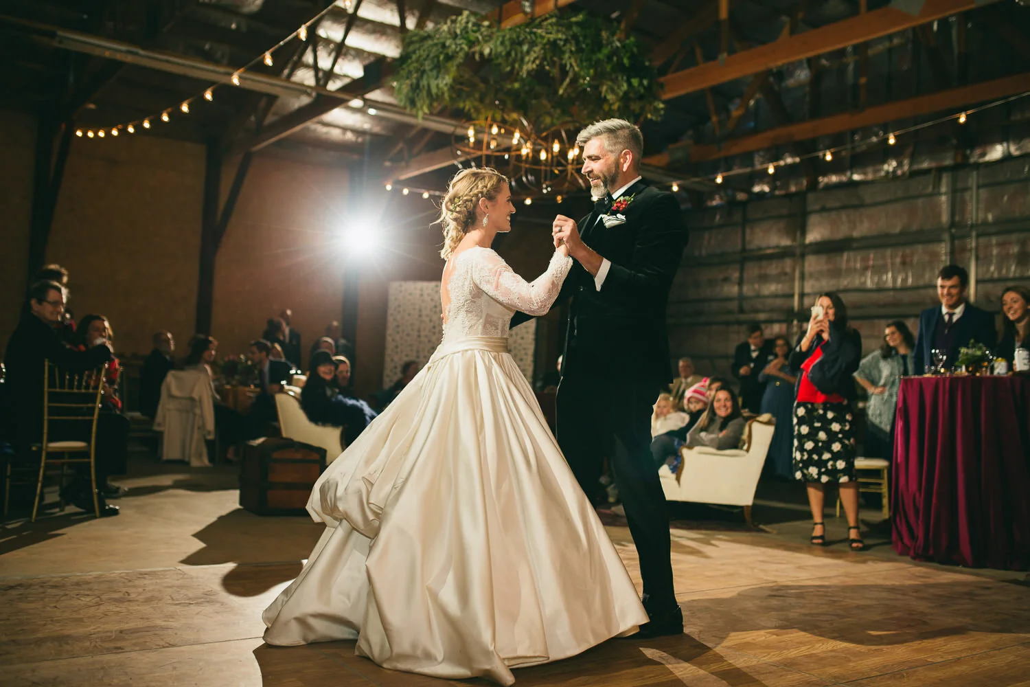  bride in hoop skirt dress and groom in black tuxedo first dance in wedding hangar 
