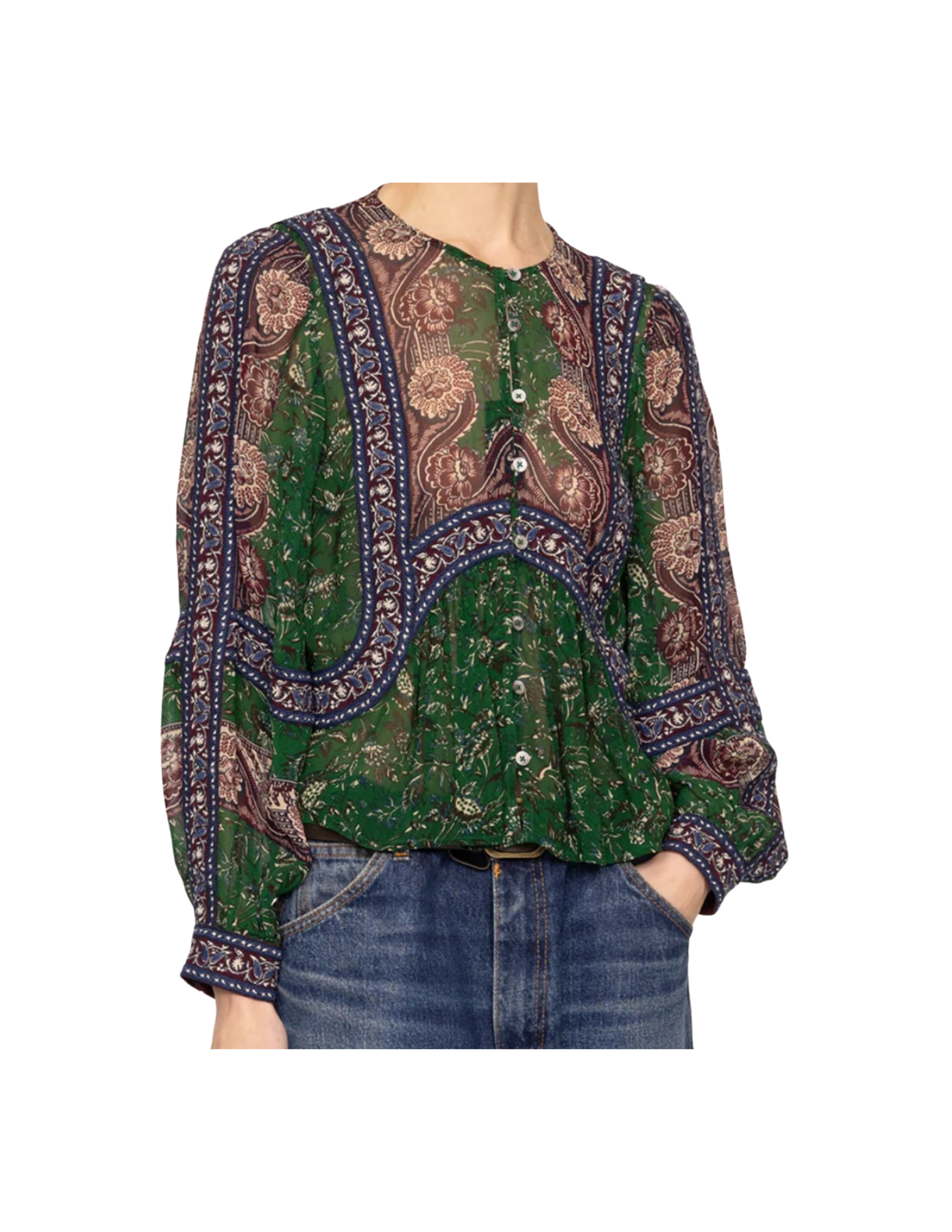 A woman wearing a green, brown, and navy patterned blouse with floral and paisley designs, tucked into blue jeans.