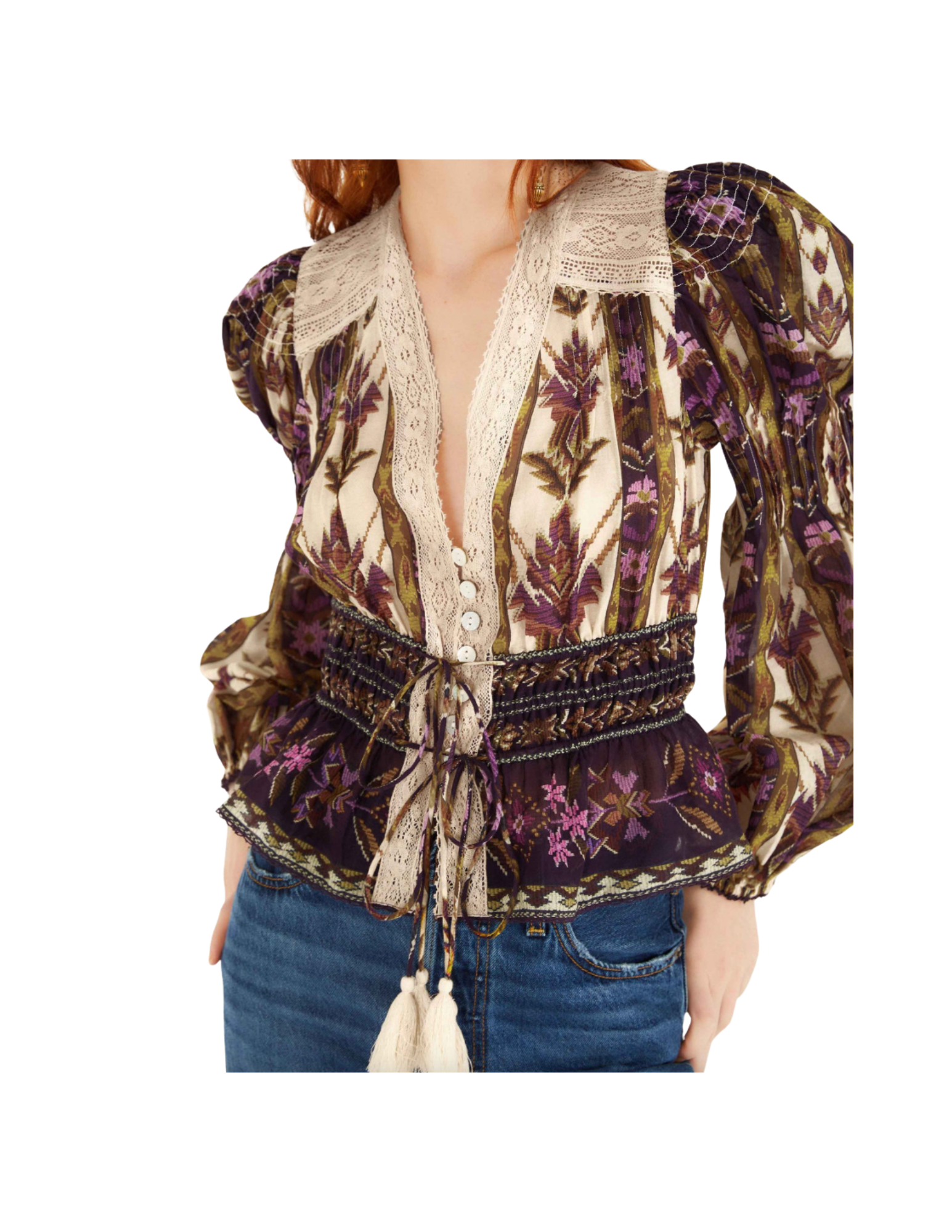 A woman wearing a bohemian-style blouse with floral and vine patterns in purple, beige, and brown, with lace and button details, paired with blue jeans.