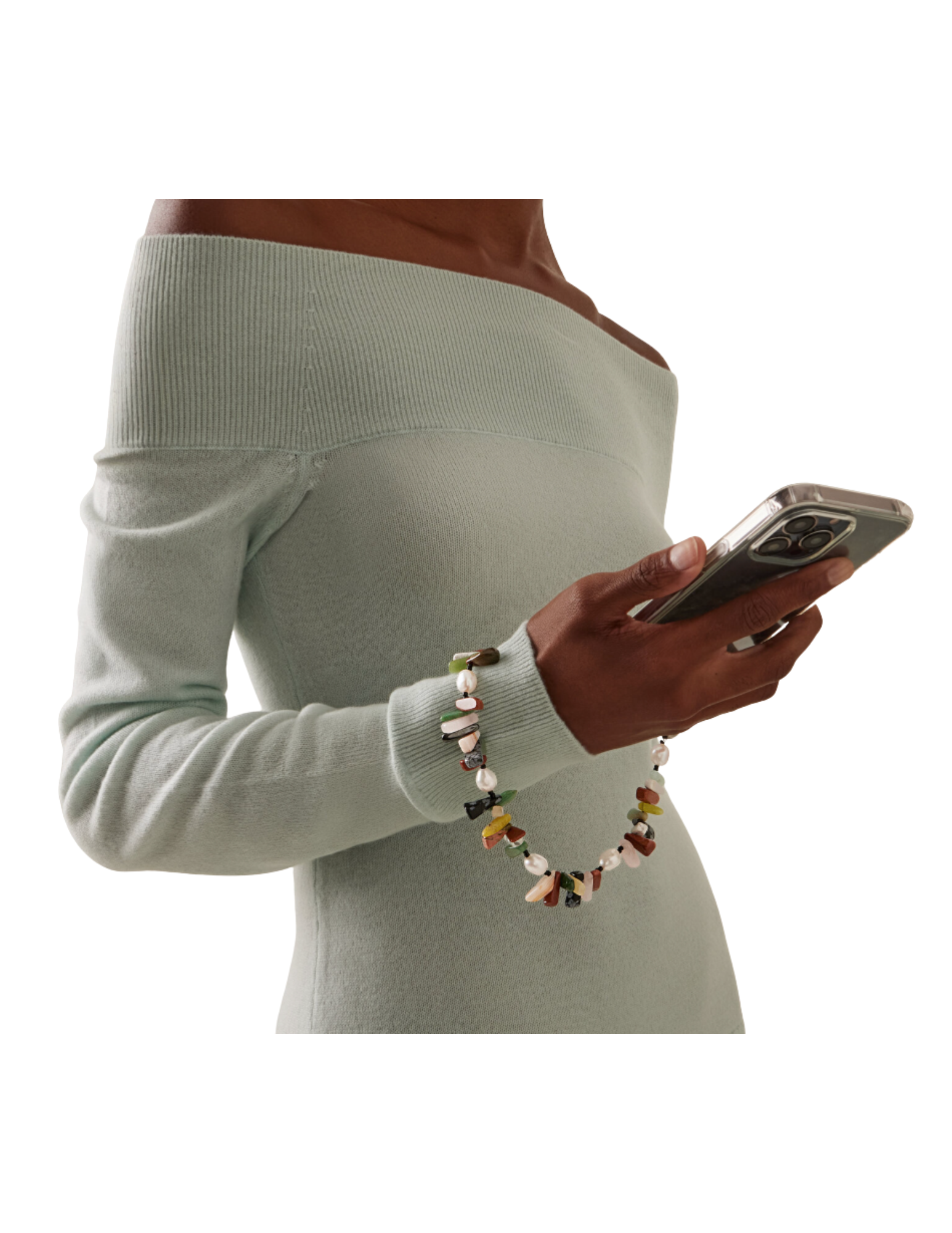 A woman in a light green off-the-shoulder sweater holding a smartphone, wearing a colorful beaded bracelet.