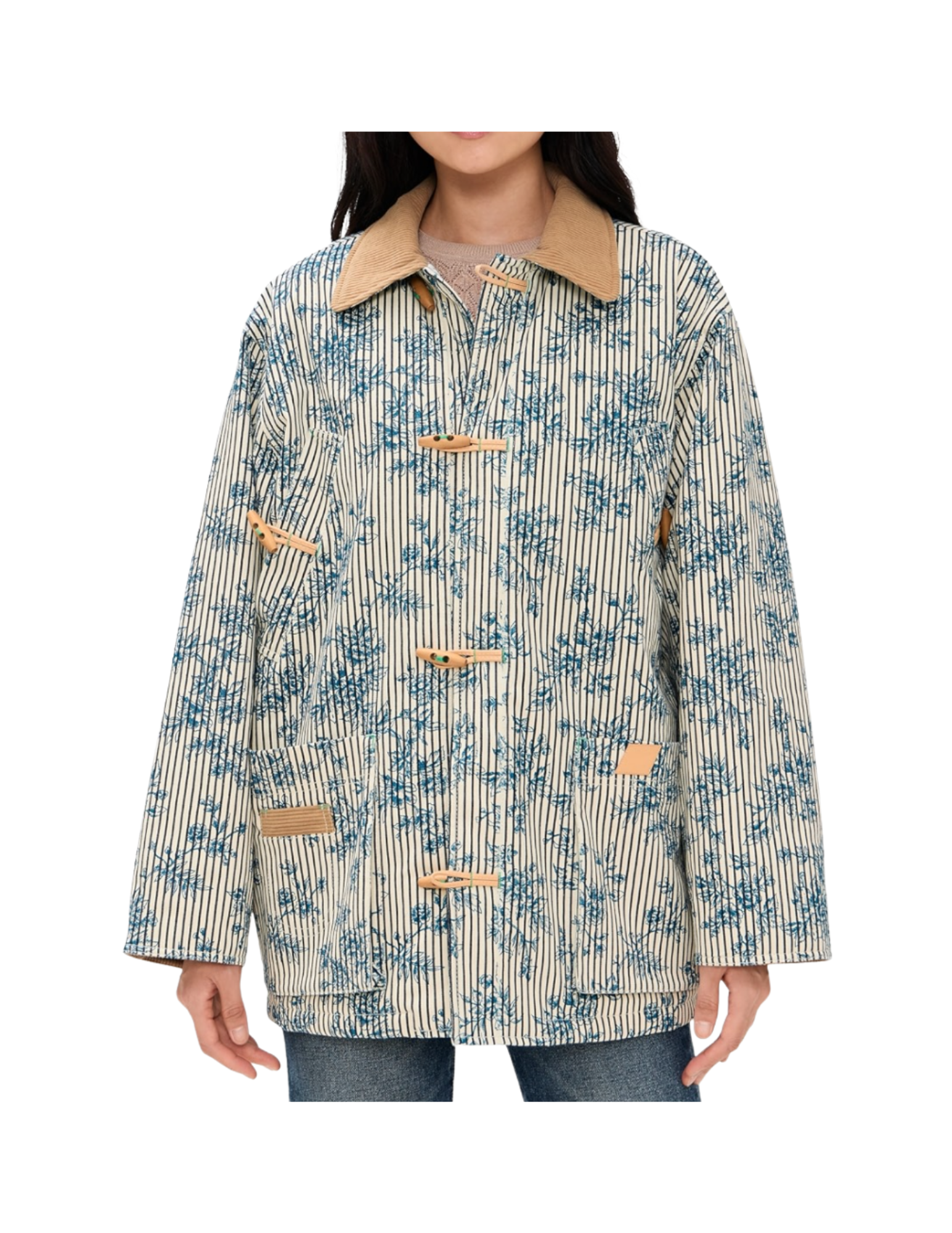A woman wearing a beige and blue patterned jacket with a tan corduroy collar, standing against a white background.