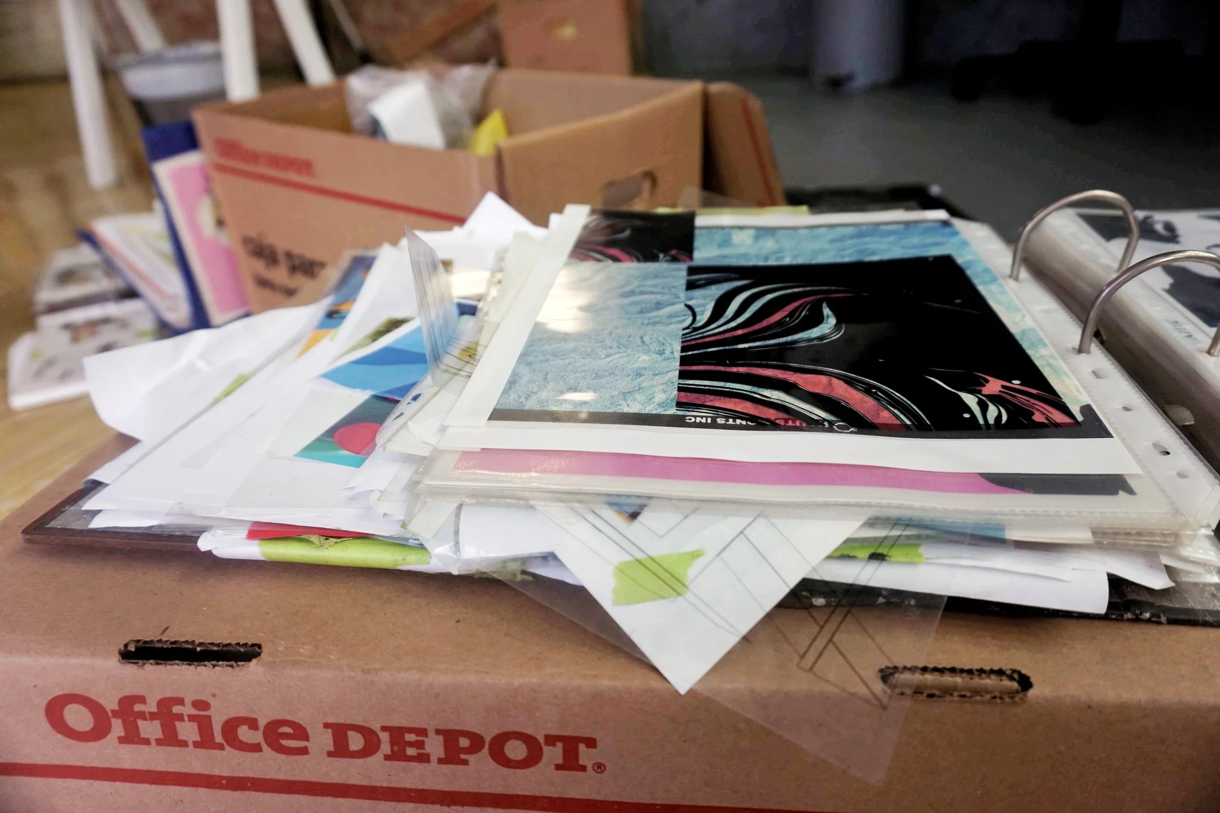 la filmina que surge y resurge se ve ahí encima, también se aprecian 2 de varias cajas de archivos que tiene este artista en su estudio, y algunos de los ampos de filminas