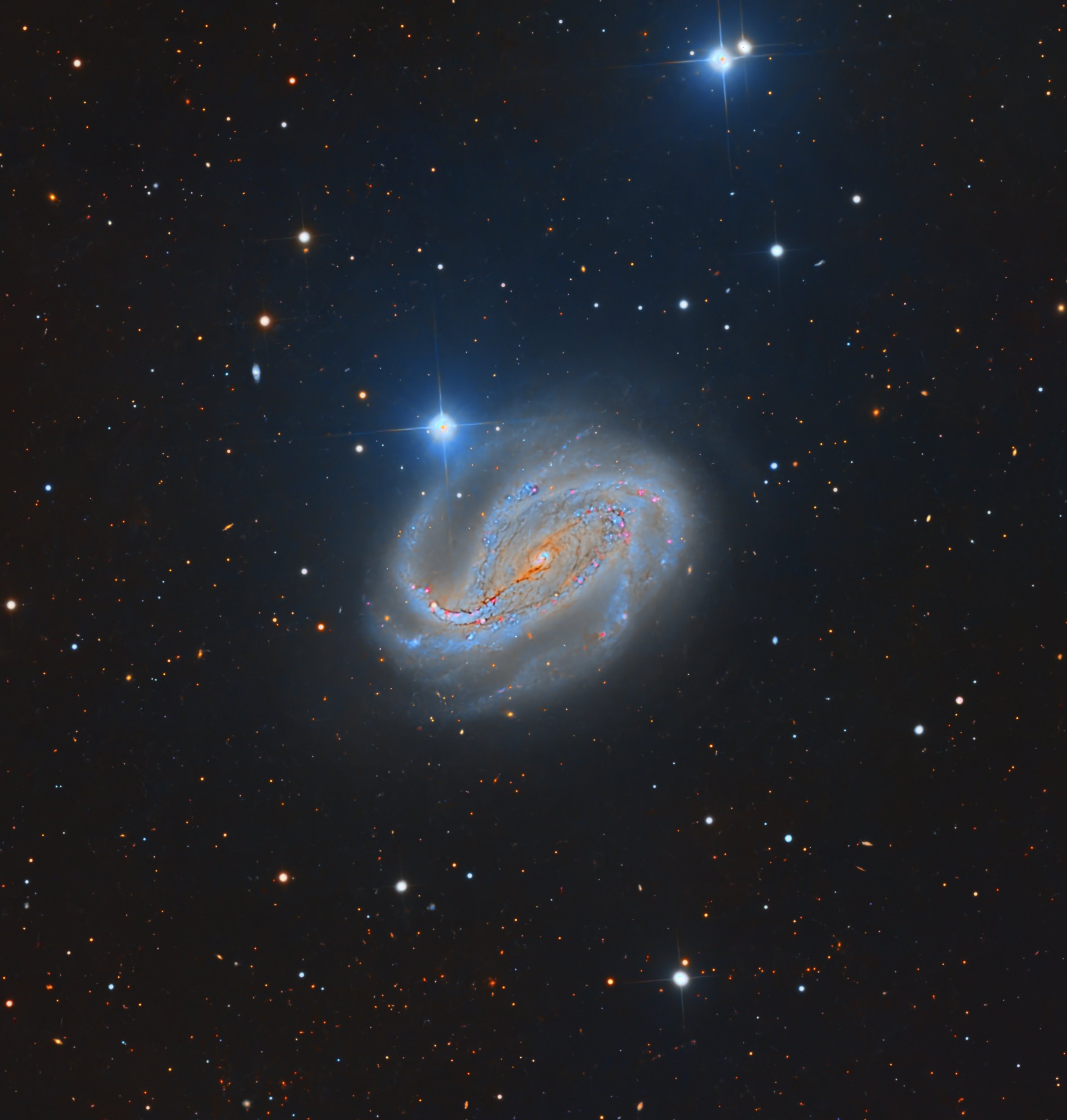 NGC 613 is a striking barred spiral galaxy about 65 million light-years away in the southern constellation Sculptor. Its most eye-catching feature is an unusually long, straight central bar, from which multiple spiral arms emerge in a somewhat chaoti