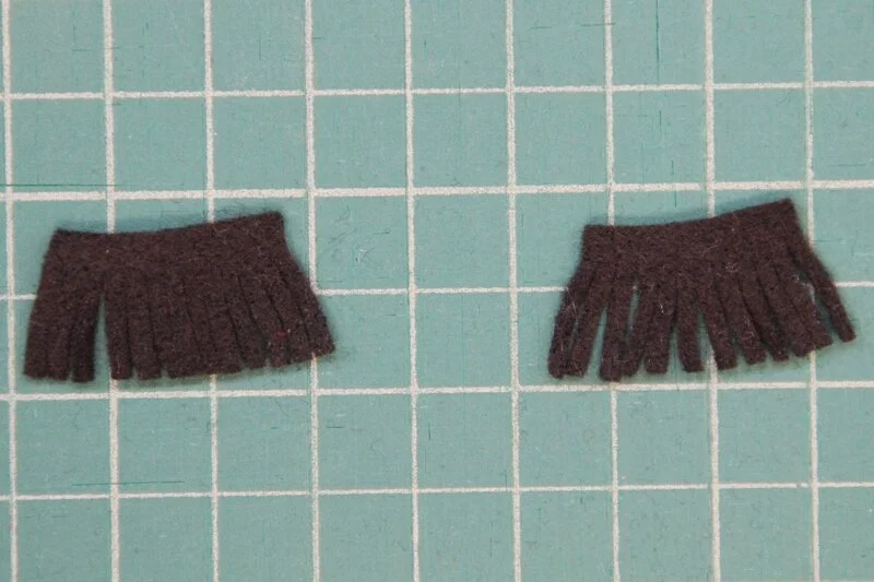 Eyelashes fringed for llama coffee cozy