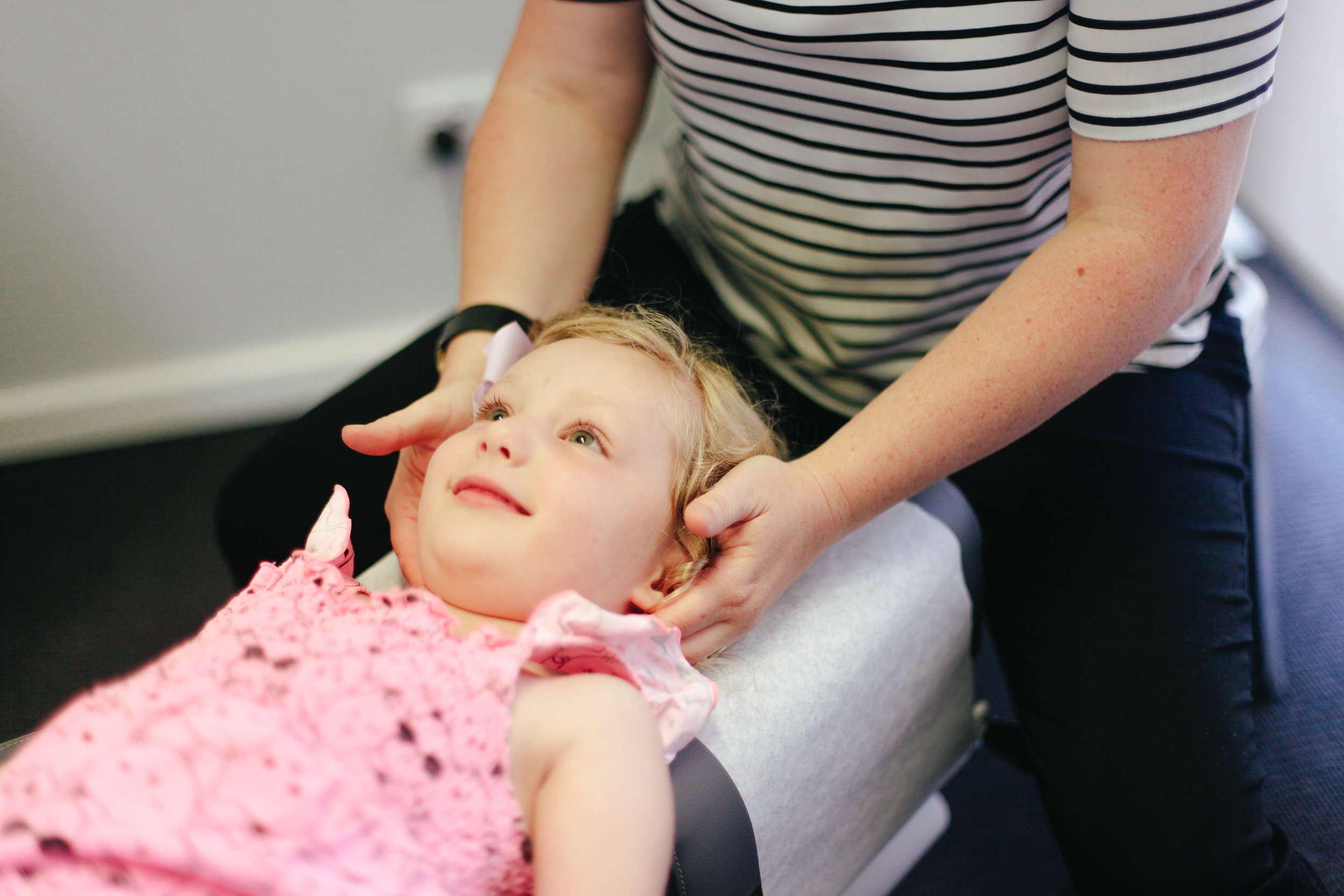 Child smiling while getting neck checked by chiropractor