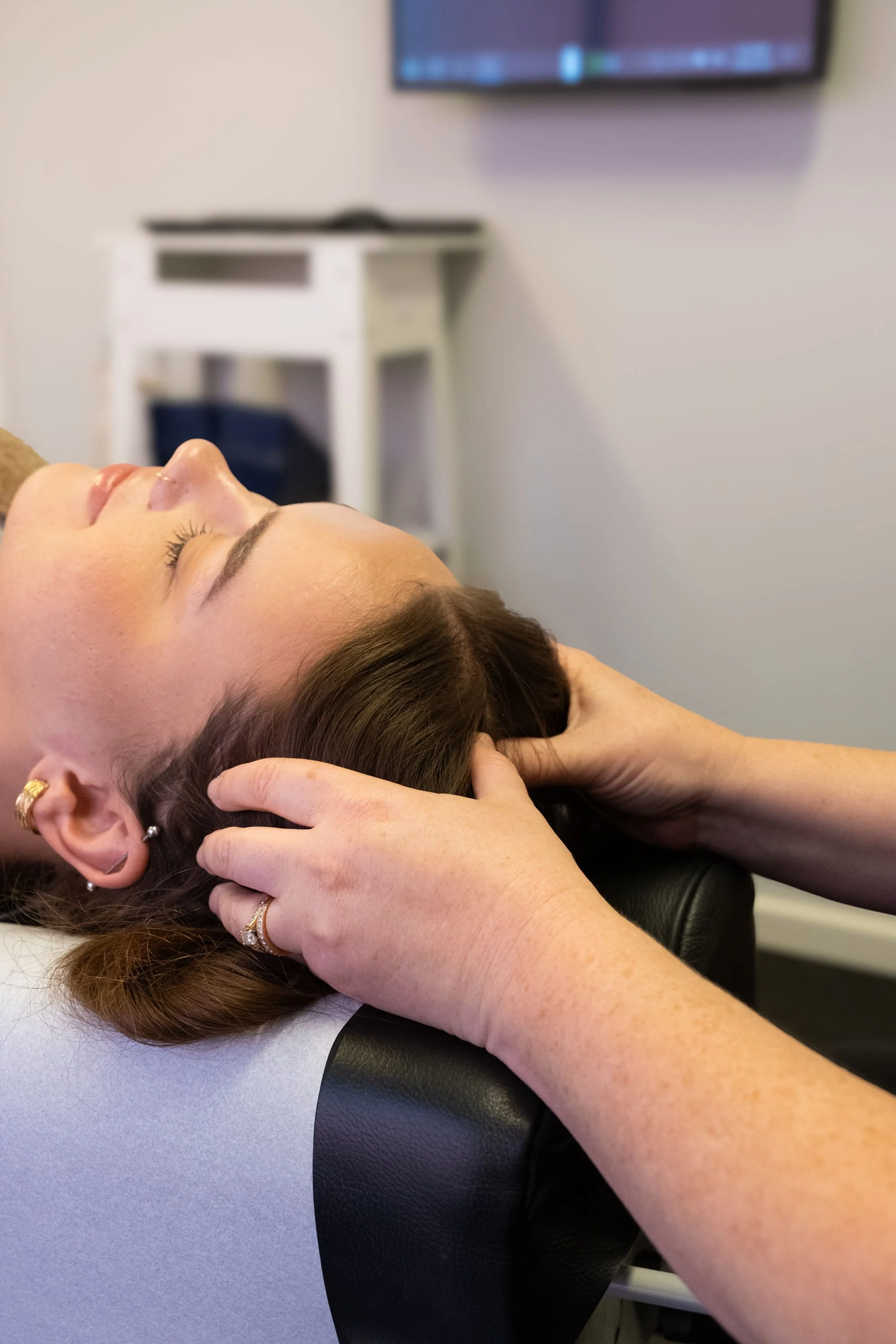 Chiropractor performing gentle manual head massage cranial work while client is relaxed