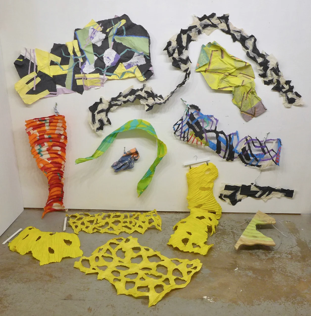 The yellow shapes are cast on HVAC ducting except the foreground one which was cast from a large trash can wrapped with thick fencing wire (below left). Ribs give the pieces some structure and volume. We put the holes in when we’re casting. The black and white “scarf” is just shapes of abaca fitted together. It was made flat, but U shaped to give it some twist and bulk even when used more or less straightened.