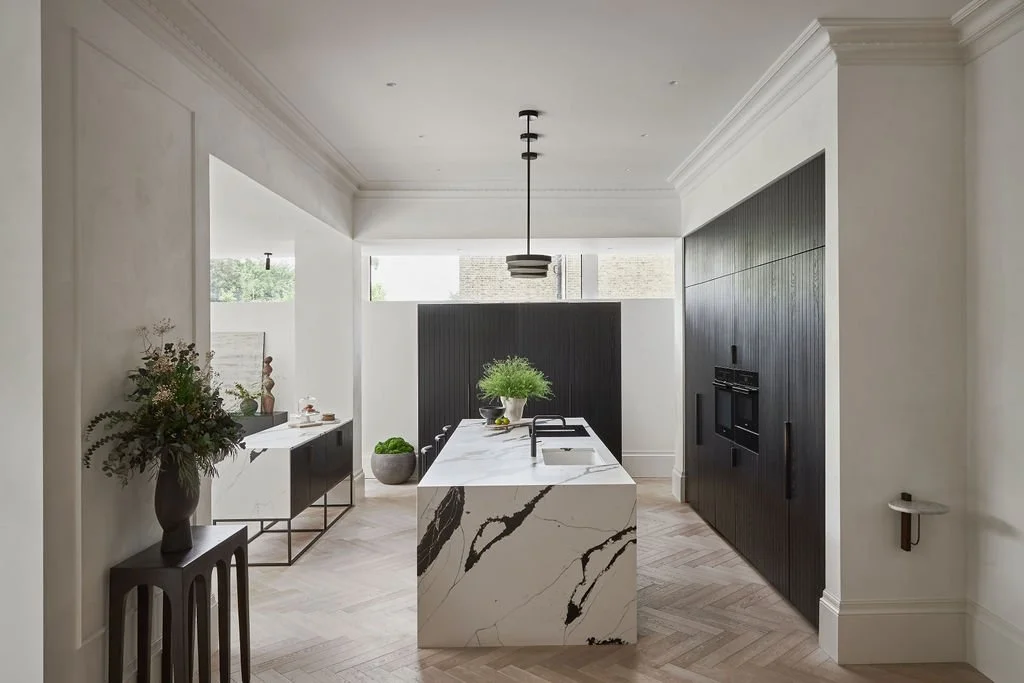 The bespoke black ash kitchen designed by VEVES features a black calacatta quartz worktop with waterfall edge and lights by CTO.