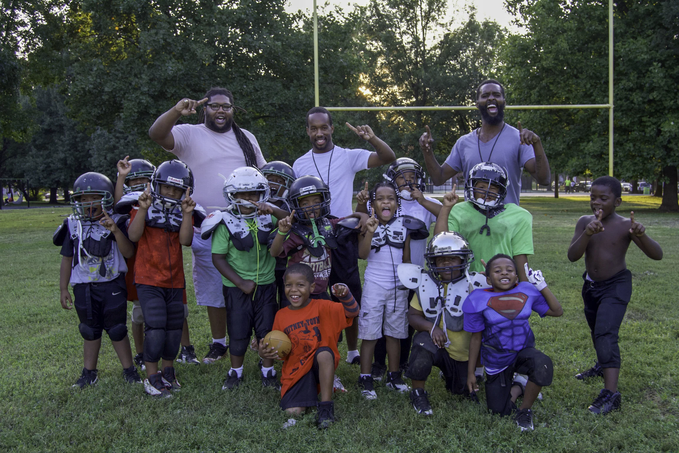 “I used to play semi-pro football. I was working out and there was this kid that would always follow me around, so I ended up working out with him. It gave me the clue that I think that I should coach. I took him to team that I started coaching. I wasn’t the head coach but a position coach. So, they let me on the team to coach as the position. Year after year, I went to different teams, so I could learn from different coaches. I wanted to be a head coach. I was on four different teams. In my mind, I’m learning from different coaches, to help me be a better coach. On everyone else’s mind, I was just jumping from team to team and winning championships. I wasn’t championship hopping but just wanted to learn. Now, I’m a head coach and I wanna put all of that together. I learned about how to discipline the kids. I was never really big on discipline, so I didn’t think that it would matter. I was thinking that it needed to start at home and it does but I needed to do it here, too. Without that discipline, they won’t listen. I also learned the skills and drills of the modern stuff. Some teams do new stuff and some stick with the old. I do a mixture of both because I experienced both. I try to keep it all together. I even try to keep up with the kids outside of football. Like on Fridays, when we don’t nothing to do, we all get together and go watch another football game. Sometimes, we’ll get together and get a hotel and they just have fun and vibe together and become a team. Defense is pulling together but offense still needs work. I played for the Jets. My last year with the them, I got MVP. I used to walk to practice everyday. Even if there was bad stuff going on, I would still walk to practice with all of my equipment. People would always tell me that I needed to coach for the team that I played for. I had coached four teams and the Jets called me and asked me if I wanted to be the head coach and that was perfect. When I went semi-pro, football wasn’t fun anymore but when I came back here, I found the fun back in football. As you get older, you have to stop playing football but you don’t have to leave the game. You gotta teach the game and that’s fun. Our challenges are that we don’t have any bleachers. Sometimes parents will sit in their car because we don’t have the seating. I go to other parks and they got bleachers. It will help us have more parent support. I go another team’s game and they have the best parent support. These kids need support. Some parents will just drop their kid off and leave. We need all parents to support because that’s what keeps these kids going. It’s important to me to be a role model in this community. People don’t understand why I do it. I wanna keep them off the streets. They could be out here doing anything but they’re out here doing something positive. I turned out good by coming to football practice everyday. When I’m with them, it makes me think about how I’m going to be with my son when he gets of age. My son is one. I have a little bitty Camaro and I pack as many kids in it, just to make sure they get to practice because some of them don’t have a way to get here. We should be a championship contender. Remember what I said. The California Jets will be a championship contender. The program is now looking like it did when I played. Catch us playing at Southern High School for our home games!” - Coach Tone (back row, center) pictured with the California Jets team & coaches in California 