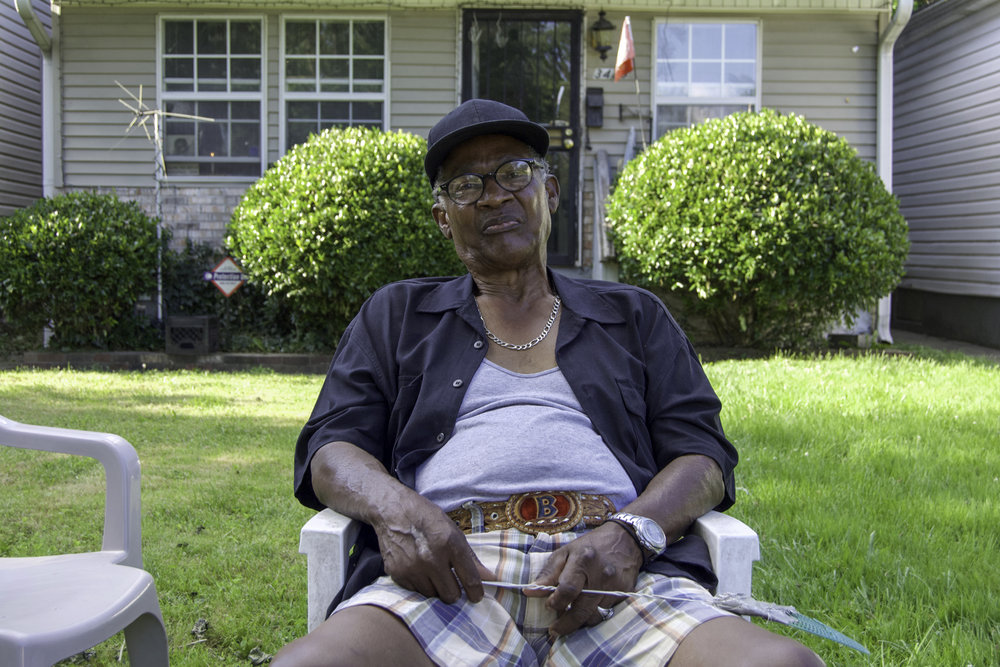 “I was born in 1945, right there on Cedar Street. The house is torn down, now. It was right there on the corner. It used to be Club Morraco and all the houses in the area, on that corner. I gotta whole lotta steps on that street - a whole lot of steps. Sam Cooke and all the singers came to Club Morraco back in the fifties. It wasn’t like it is now, you know, with all the killings and stuff. We had our little spats but they were fists fights and you would go on about your merrily way. We didn’t have any gangs. We had our own little crew that we ran around with. As far as fighting and shooting, that wasn’t going on with the younger people. The older people were the ones doing all the shooting. You didn’t play with them older people. I was born and raised in the Russell area. We moved from Cedar Street to 19th, between Walnut and Madison Street. Our address was 513, where that empty lot is, where Jay’s Restaurant used to be. There used to be a house right there on that corner. I had a good time, growing up. I didn’t have nothing to squawk about. I come from a good family with five boys and two girls. It was kinda rough. Some people had food on the table and some people didn’t. We were fortunate. My father was a minister and he had his own church. We ate well but back in the forties and fifties, it was rough but we made it. That’s the main thing - we made it. I graduated from Central High School in ‘63 and went in the Navy and never looked back. I left in ‘63 and came back in ‘67. I stayed in the navy for four years, oversees. I stayed near the French Riviera. After being over there, I moved to New York and stayed for a while but I decided to come back home. When I came home, I had a good time here. I went to school and worked. I worked at Olin Mathieson, the powder plant. I left there and went to the P. Lorillard Tobacco Factory that was on 30th and Muhammad Ali. I spent 34 years down there. I started working there in ‘72 and retired in ‘06. I was a mechanic and worked on machinery. When I moved back, I moved out in the county, off Manslick Rd. I met this young lady and we got married and eventually separated. I left there and moved to St. Matthews, out in Oxmoor, then I came back to the West End. I love the West End. I came back to West End about 20 years ago. I like to sit out. My friend comes around and tells me that I’m always meddlin’. I’m not meddlin’, I just like to know what’s around me. I like to meet new people. I know everybody up and down this block. We don’t have any problems in this area. I’m out here every day. I won’t sit out in the sun when it’s too warm out. I gotta shade tree that I’ll sit right under. I’ll get a breeze every now and then but as long as this bad boy don’t fall, I’m cool. I sometimes leave here and will walk down to the church, down the block, but I belong to Bethel Baptist Church on 35th and Garland. I’m here because I like being here. I live by myself because me and my girlfriend couldn’t get along. We separated. I had another girlfriend and we couldn’t get along either and we separated, too. I don’t have no ill feelings about the West End. I’ll never talk bad about the West End. I hear people do that all the time. I always say that the West End is the best end! There’s crime everywhere; you can’t get around it. Time changes and nothing stays the same. Like I tell people, “Seasons change, so you know time’s gonna change.” Nothing stays the same. Hold on and don’t take no wooden nickels. Seasons change. Nothing is perfect, so hold on and it’ll get away from you. Don’t give up!” - Benjamin, Parkland