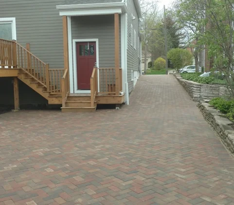 Driveway - Glencoe, IL
Normal.dotm
0
0
1
73
419
Florida State University
3
1
514
12.0
0
false
18 pt
18 pt
0
0
false
false
false
/* Style Definitions */
table.MsoNormalTable
{mso-style-name:"Table Normal";
mso-tstyle-rowband-size:0;
mso-tstyle-colband-size:0;
mso-style-noshow:yes;
mso-style-parent:"";
mso-padding-alt:0in 5.4pt 0in 5.4pt;
mso-para-margin:0in;
mso-para-margin-bottom:.0001pt;
mso-pagination:widow-orphan;
font-size:12.0pt;
font-family:"Times New Roman";
mso-ascii-font-family:Cambria;
mso-ascii-theme-font:minor-latin;
mso-fareast-font-family:"Times New Roman";
mso-fareast-theme-font:minor-fareast;
mso-hansi-font-family:Cambria;
mso-hansi-theme-font:minor-latin;
mso-bidi-font-family:"Times New Roman";
mso-bidi-theme-font:minor-bidi;}
On this particular driveway in Glencoe IL, we had an existing dry stack retaining wall that was aged and out of line. In order for the soldier border to have been laid straight the wall was removed, restacked and had permeable landscape fabric behind the wall to keep soil from passing through the wall. There were two existing gutter down spouts that needed water diverted. The downspout trench was dug and pipes lay on a sand bed. An assortment of fittings and pipes brought the water to the backyard.