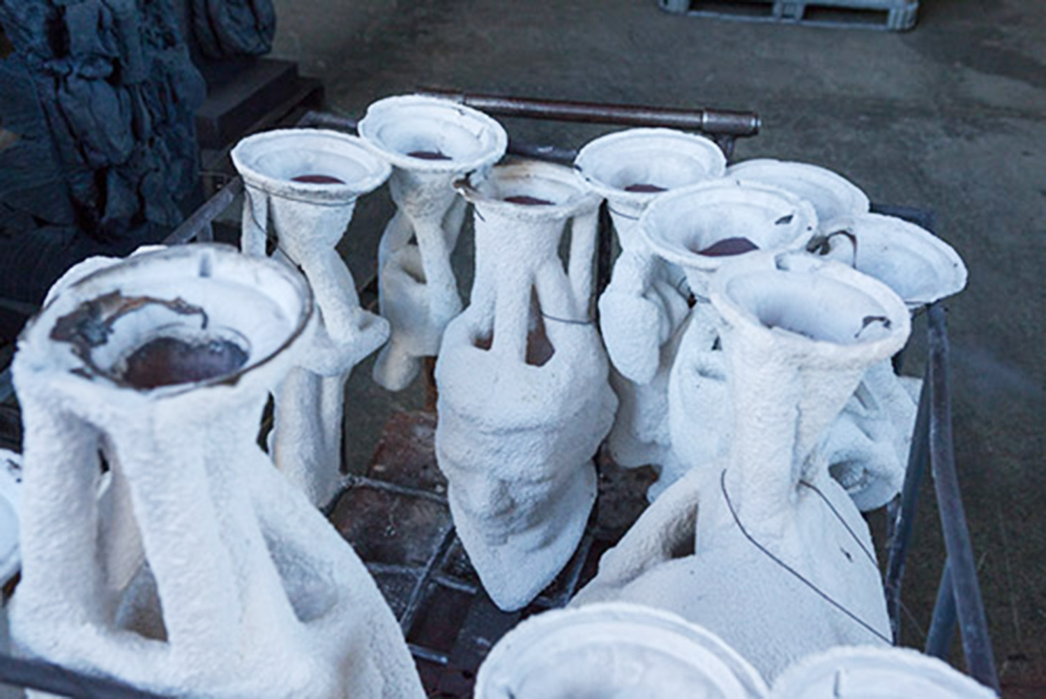 You can see the statue head, here, cooling after being filled with molten bronze. When it has been thoroughly cooled the ceramic shell will be broken off and the cast bronze will be cleaned, welded together, and chased (retouched with metal tools) to match the artist's original.