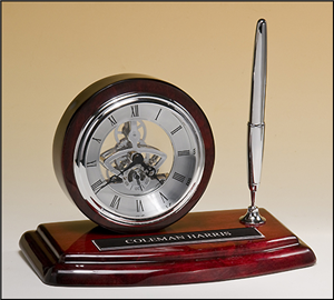 Skeleton Desk Clock Skeleton clock with sub-second dial, silver movement and pen on rosewood piano-finish base. Price of $172.00 does not include engraving. Engraving is the greater of $24 or 30¢ per character. Overall size is 8.25 x 5″. Lifetime guaranteed movement
