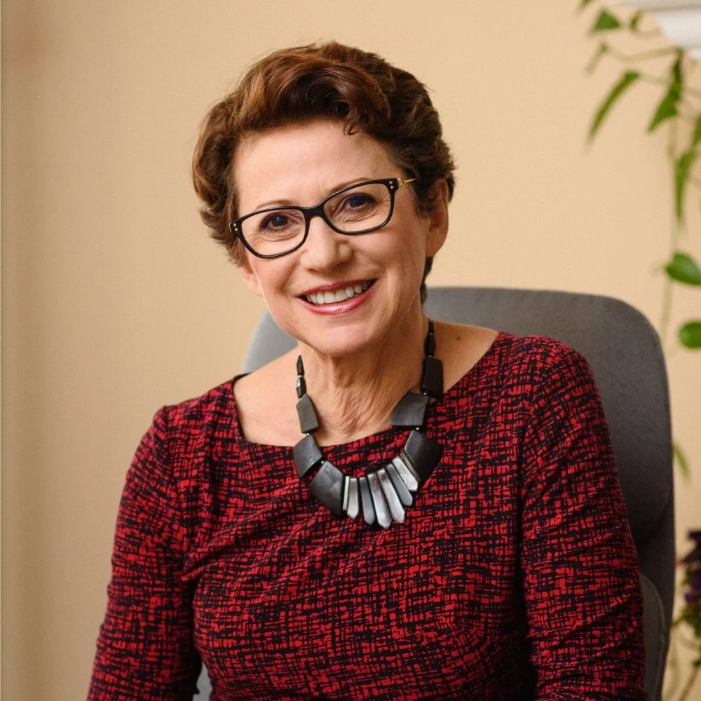 Vikki sitting in a chair, smiling.