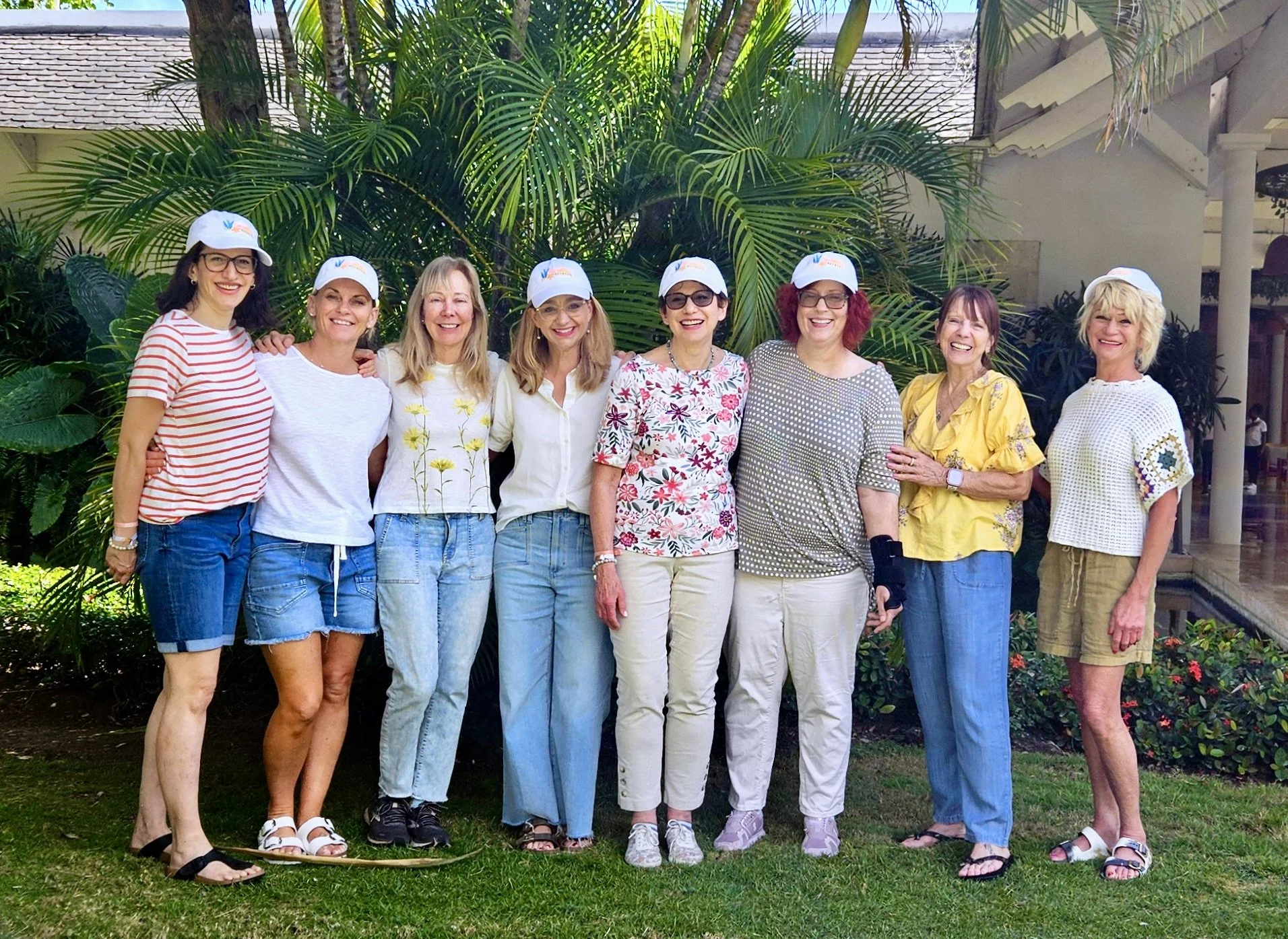 8 women smiling for the camera in warm weather.