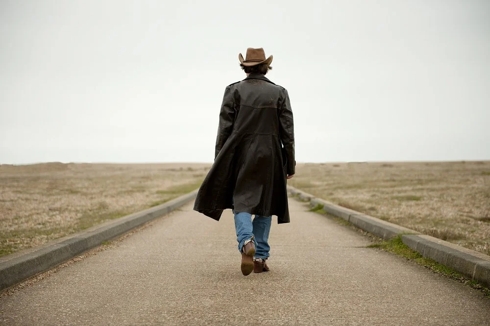man walking away on a deserted road.