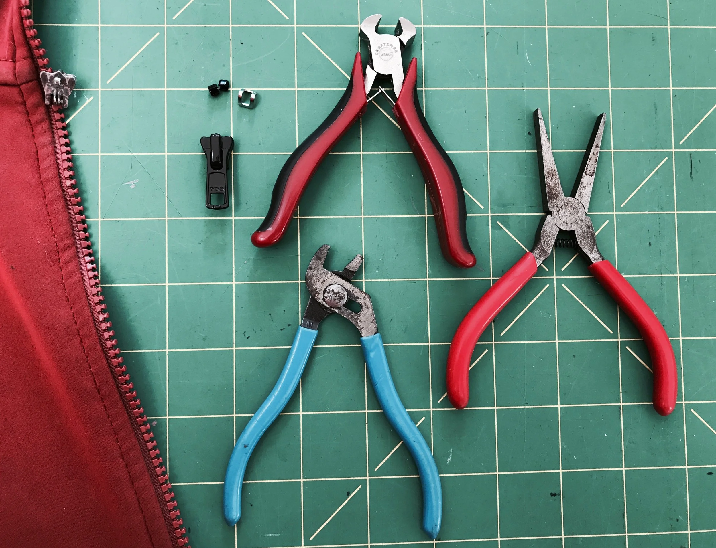 Tools of the trade. Replacement end stops, replacement zipper slider, small end nippers, small channel lock pliers and optional flat needle nose pliers. The whole job can be done with a multi-tool in the field, though these tools do make it a bit easier. Note the various end stops in the upper left of the picture. various sizes and styles are available.