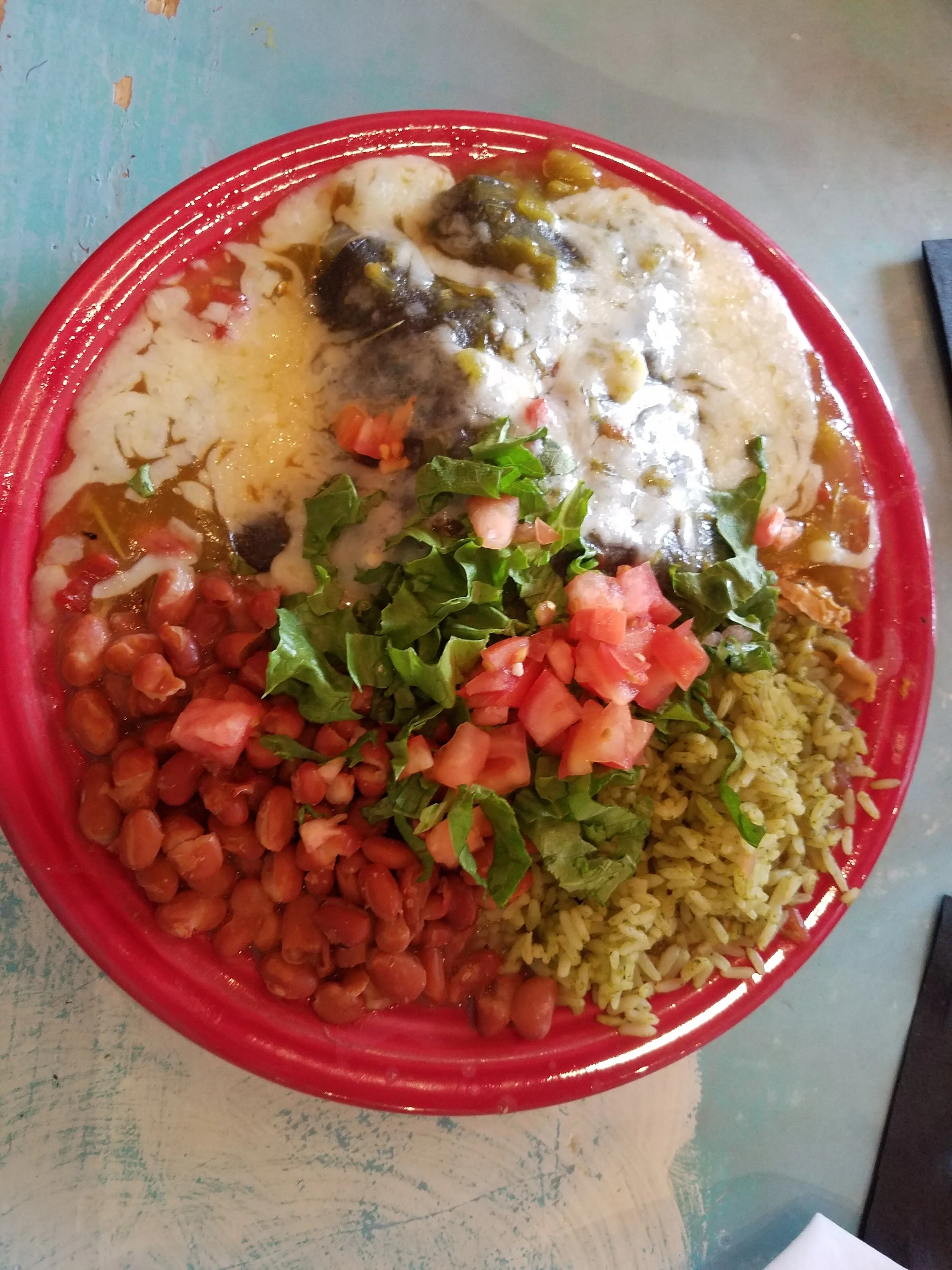 Rolled blue corn tortilla chicken enchiladas with green chile and white cheddar, pinto beans and rice at the Range Cafe in Bernalillo