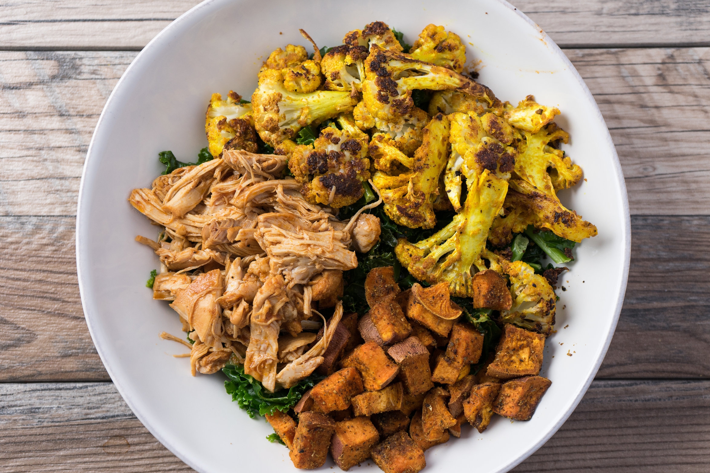 BBQ chicken bowl with roasted cauliflower, roasted sweet potatoes and steamed curly kale