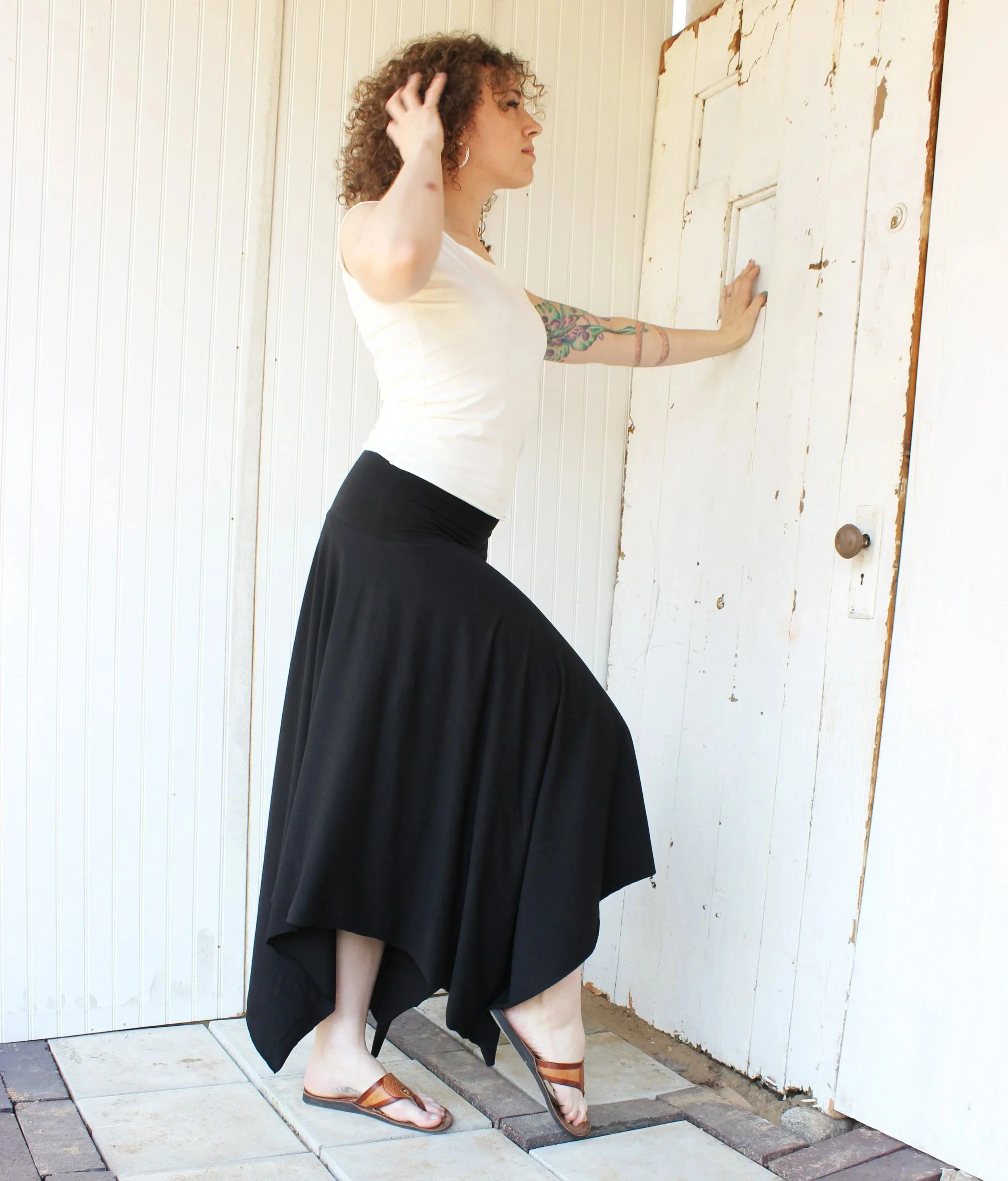 black flowing circle skirt with uneven cut shown on curly haired size medium model.  Made of bamboo and organic cotton.  Boho minimalist style organic women's clothing skirt.