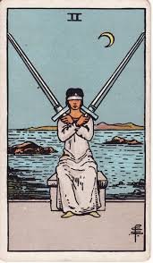Tarot cards, two of swords. A woman blindfolded holds two swords, a symbol of differentiation. SDhe is able to use her own inner guidance to make a clear choice.