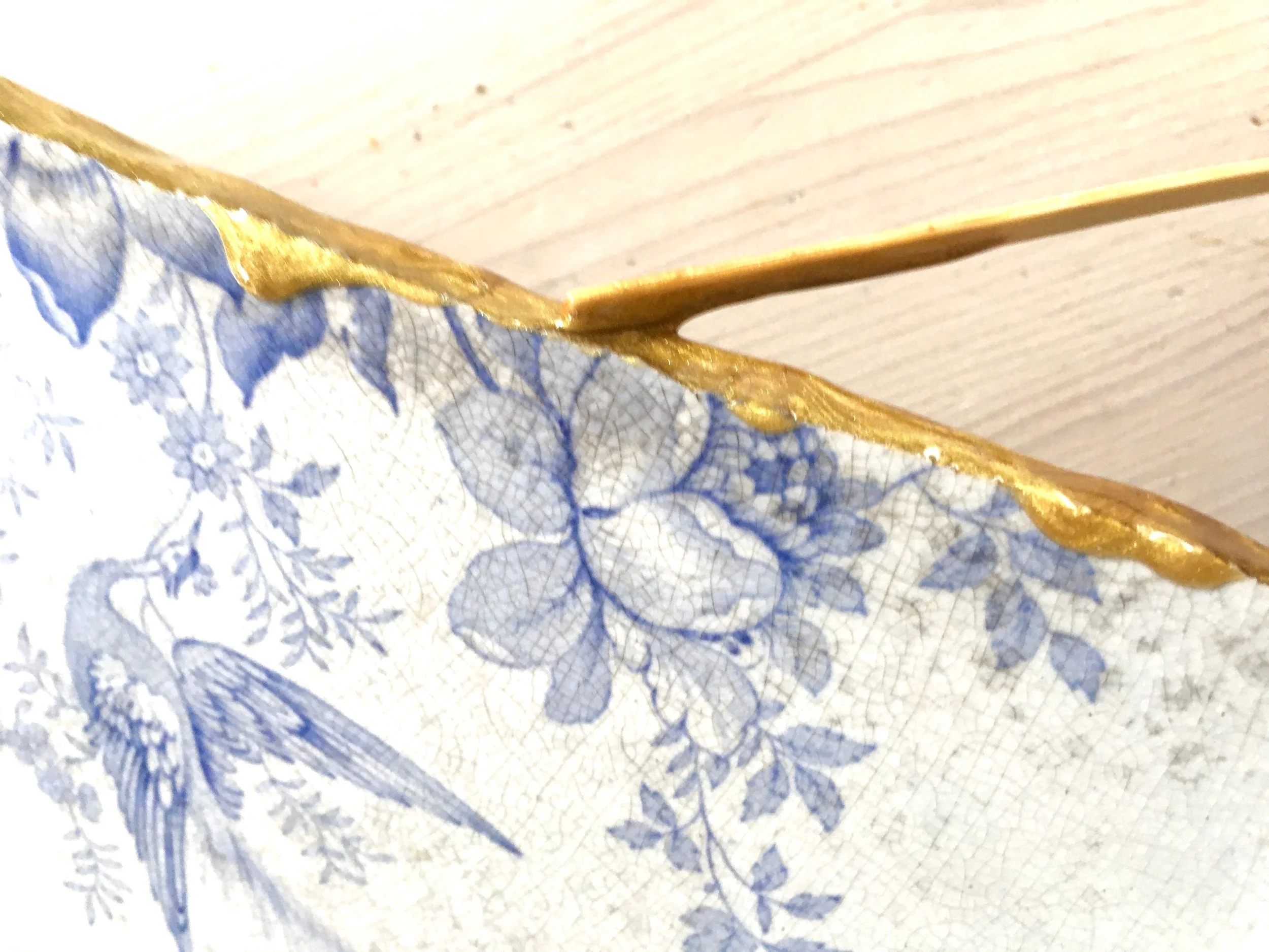 4. Use the lolly stick to spread an even layer of gold adhesive along both broken edges of the china. 5. Wait a minute for the adhesive to start going off before bringing both halves together and then holding together firmly until the adhesive has set. Before the adhesive completely hardens brush over with gold dust.