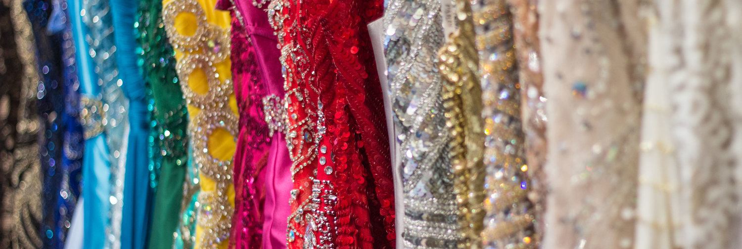 close up of pageant dresses in all different colors, most of them beaded.