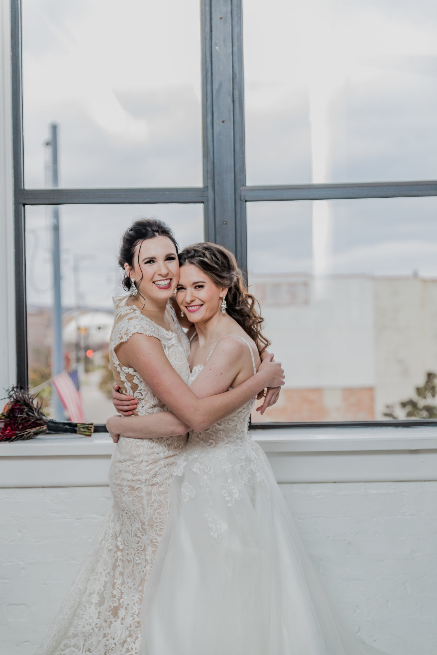 Two women in wedding dresses hugging each other.