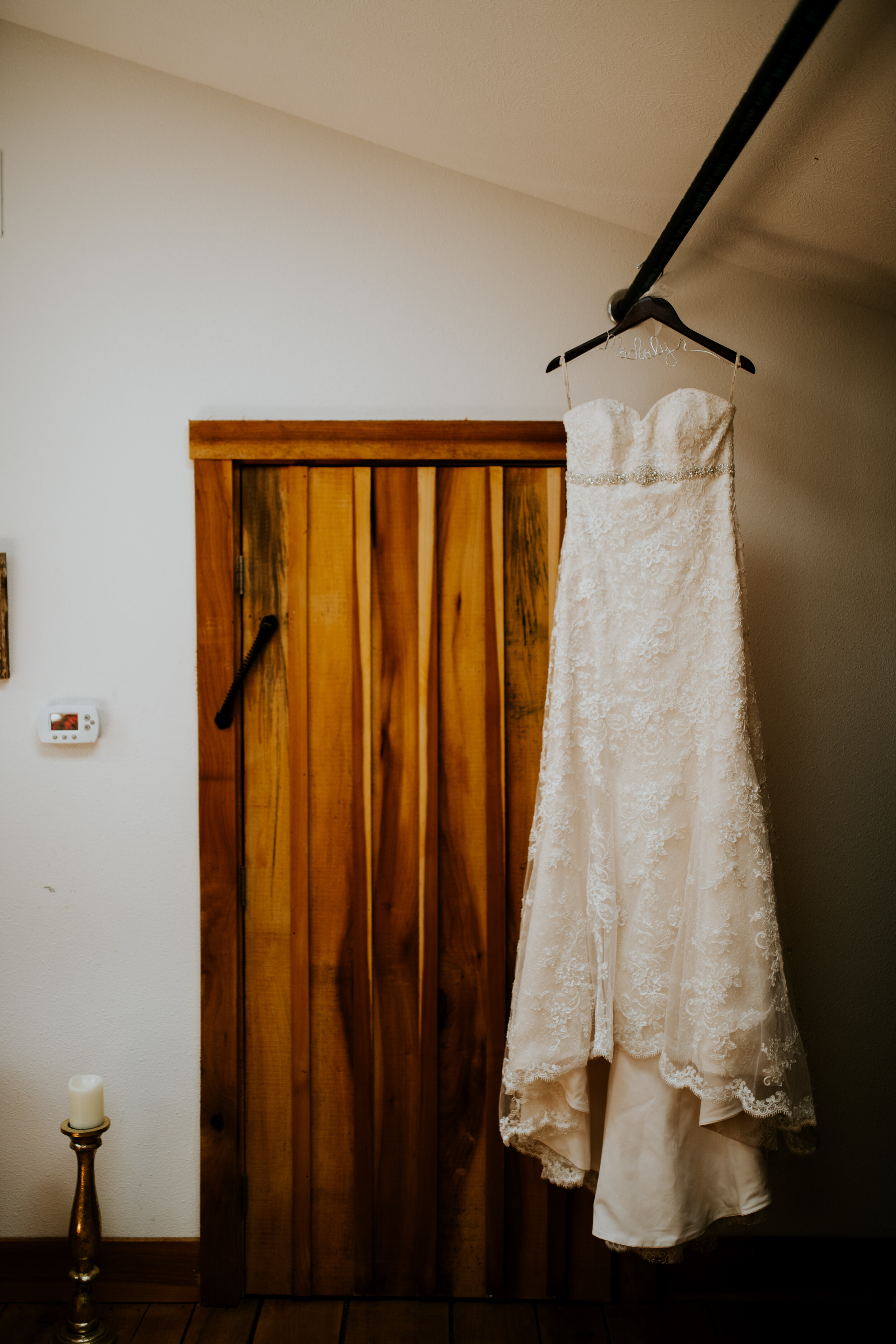 Maggie Sottero Bridal gown on hanger in front of wooden door