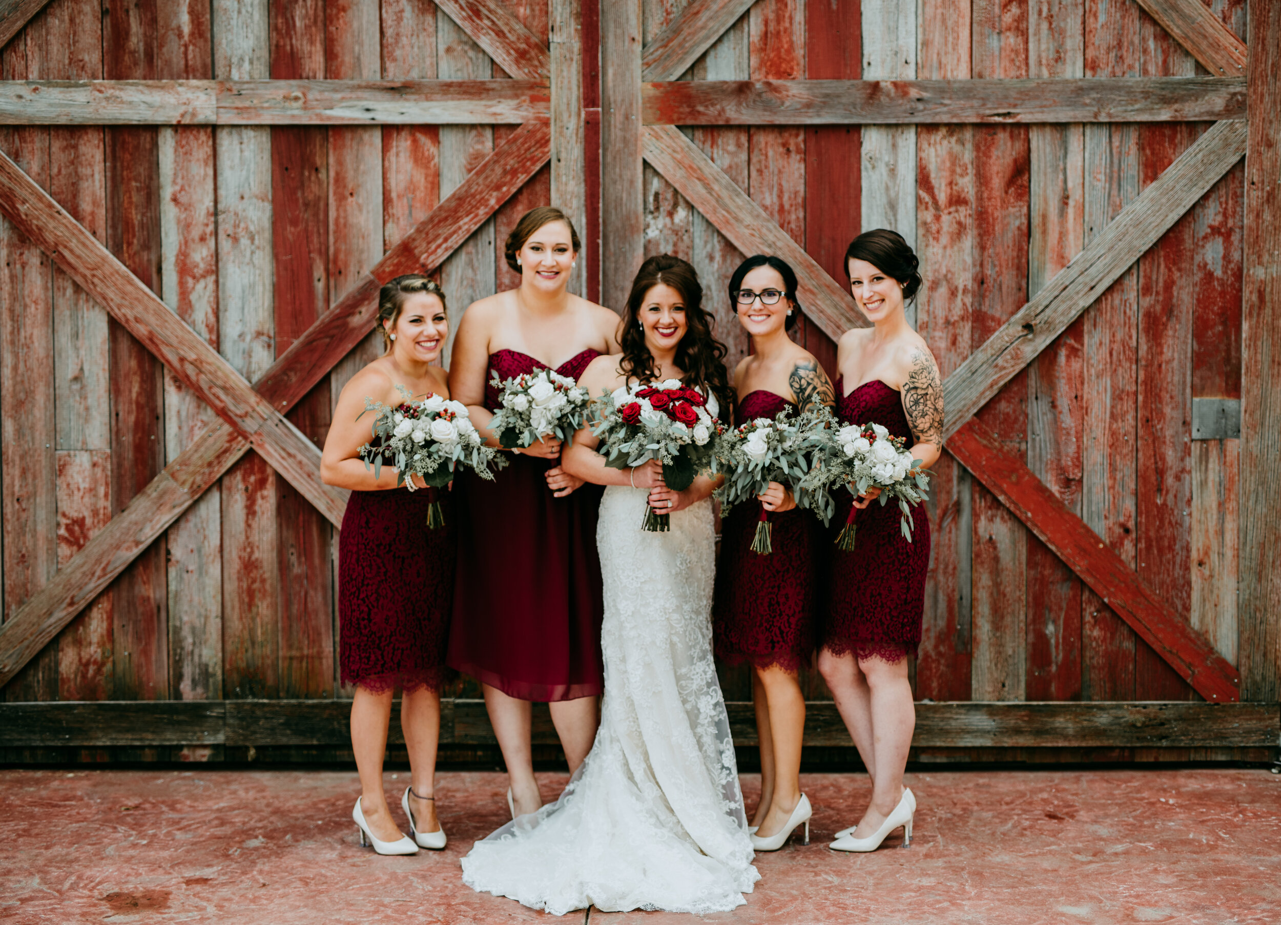 bridesmaids in red with bride in front of barn doors