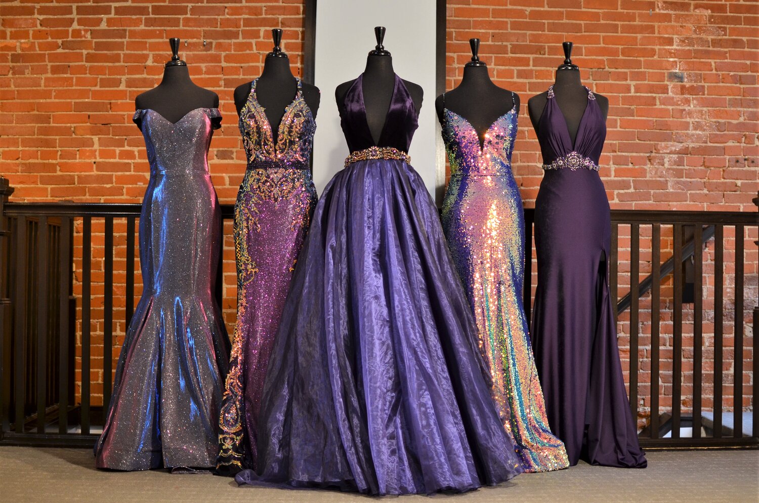 5 different purple pageant dresses from inside the store on mannequins.